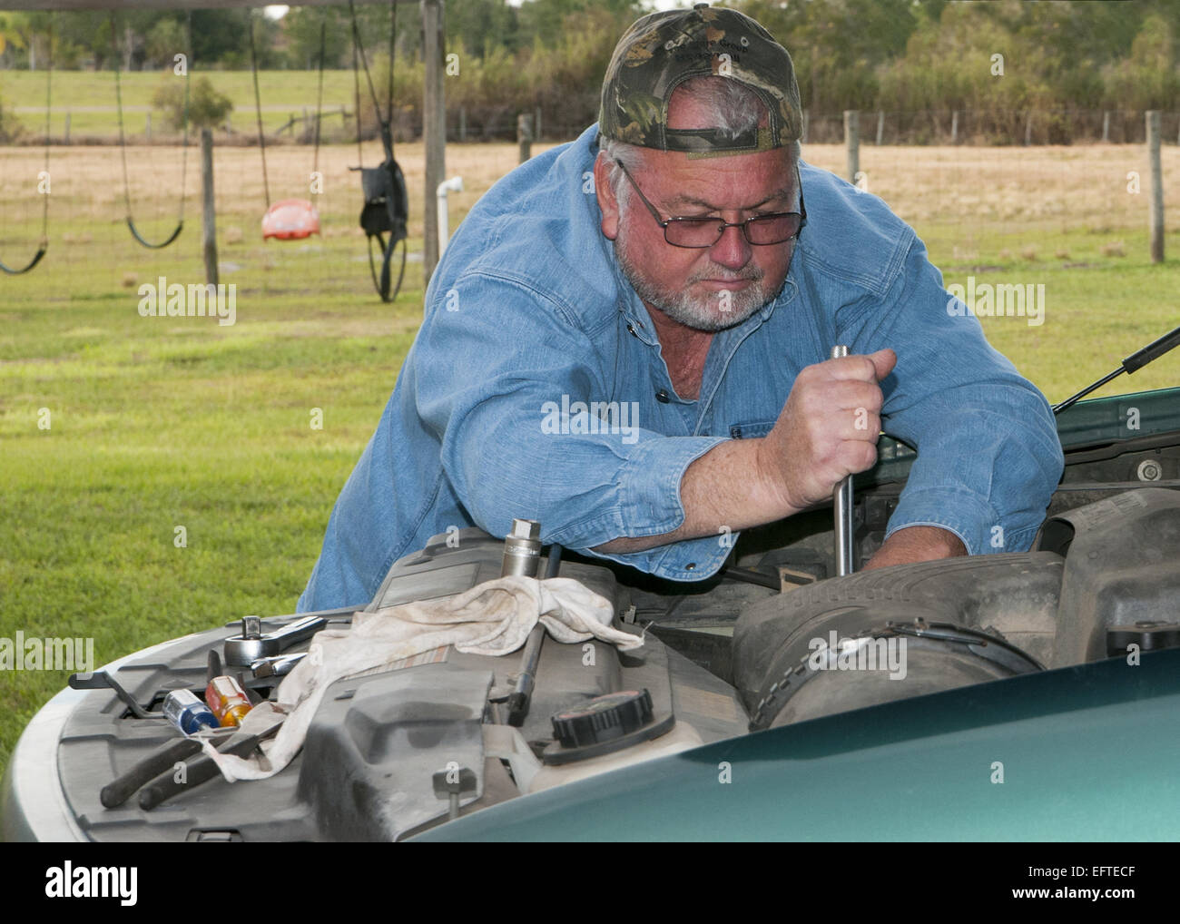 Man working on repairing his vehicle at home. Stock Photo