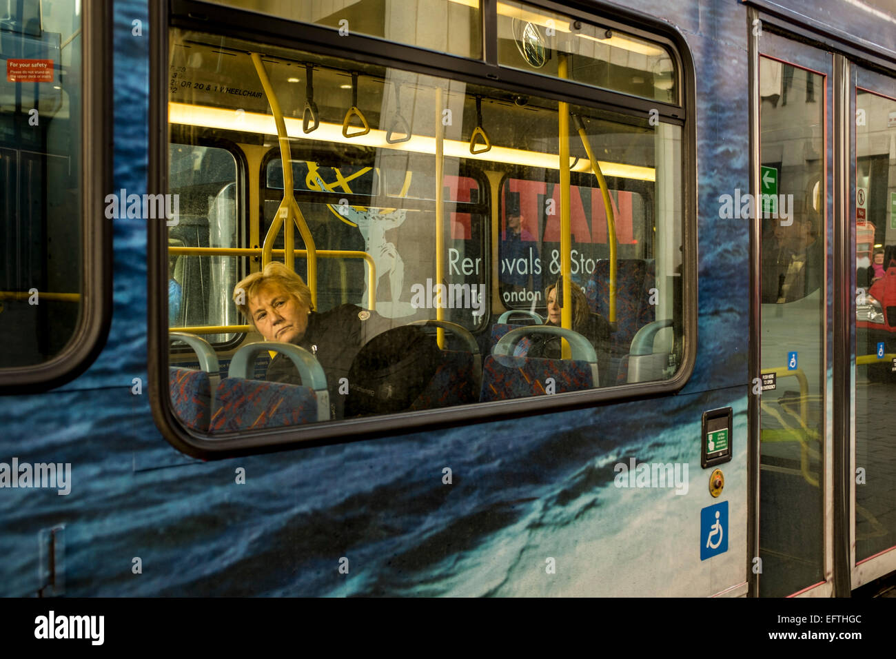 A woman on a Dockland Light Railway train in Lewisham waiting for the train to depart Stock Photo