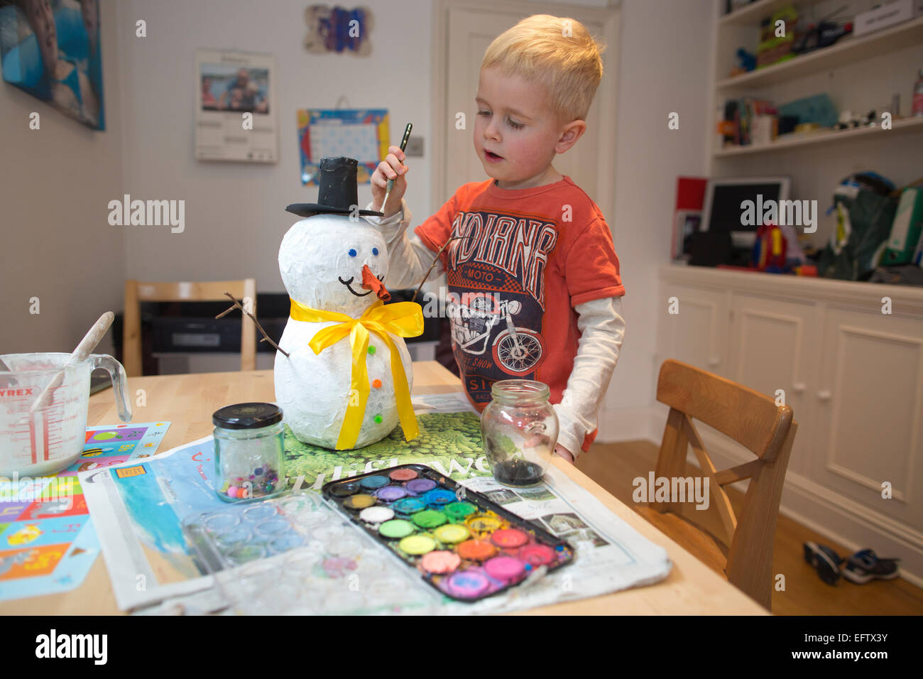 Four (4) year old boy making a paper mache, papier måché snowman as part of his school homework, UK Stock Photo