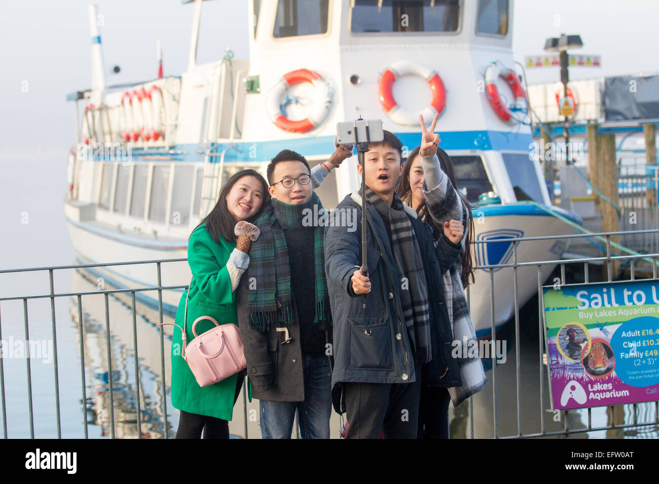 Tourists using mobile smartphone Iphone  selfie - selfies stick  to take photos & video of themselves Stock Photo