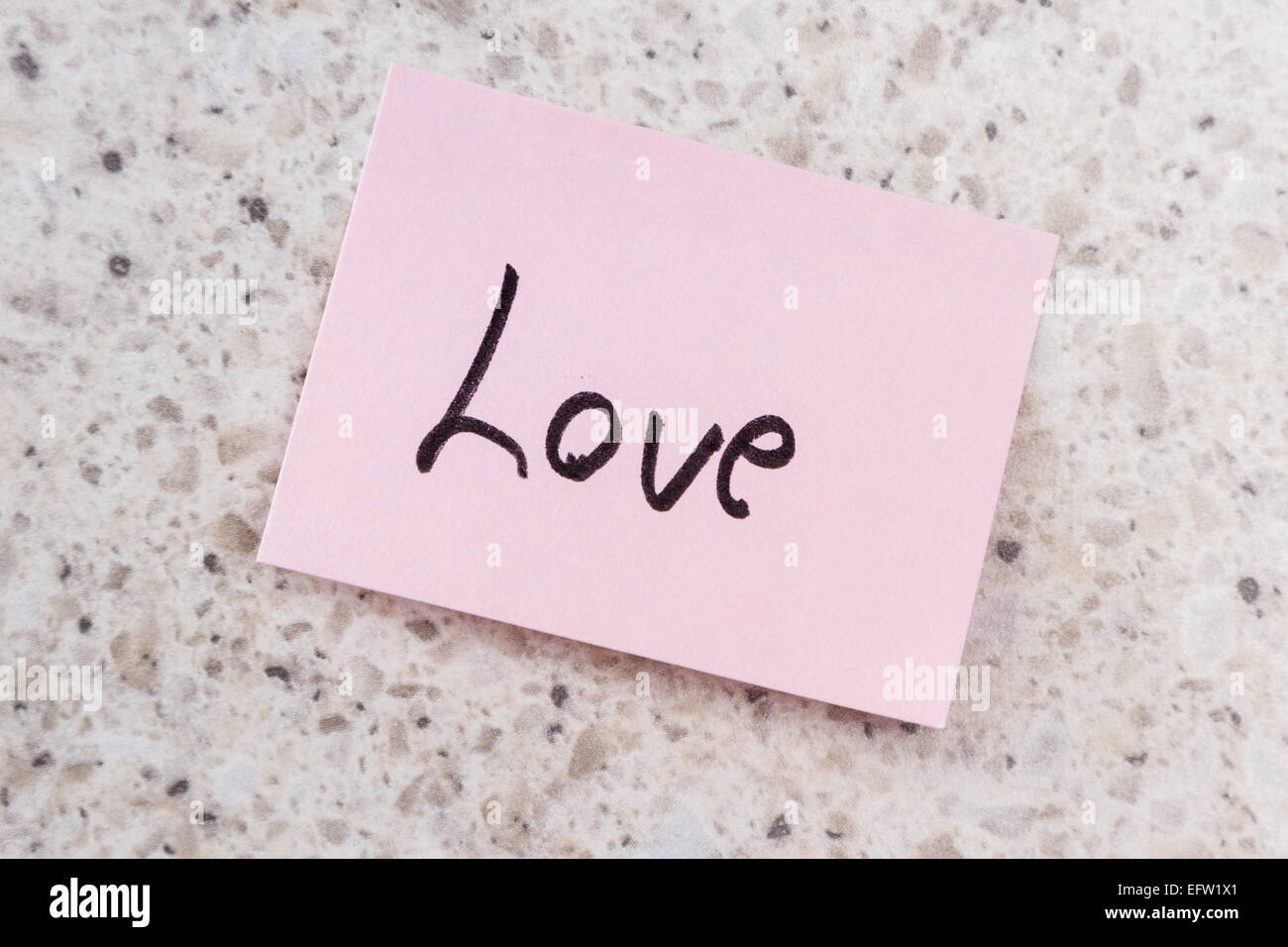 Small Pink Note With The Word Love On An Office Desk Background