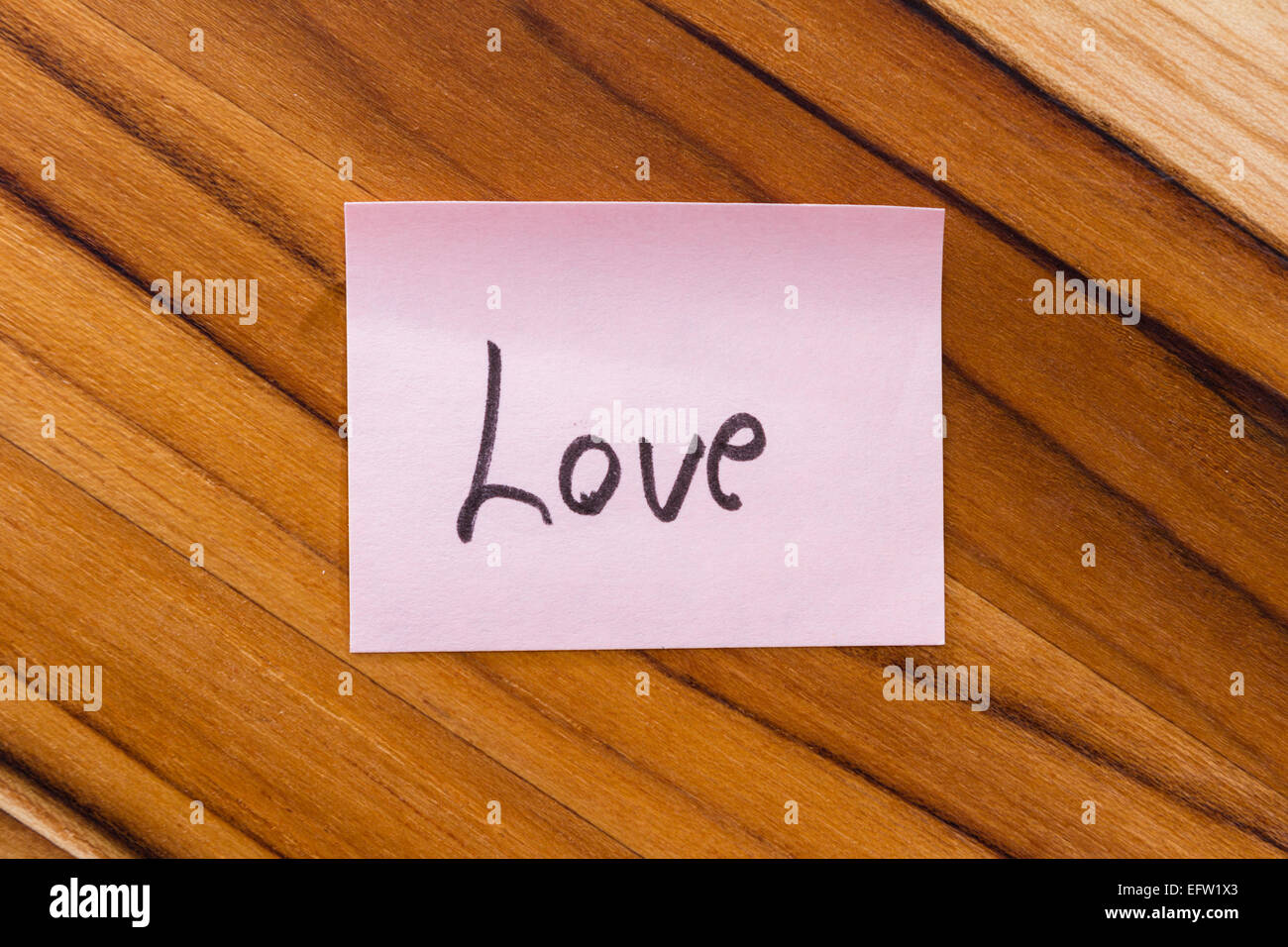 Small Pink Note With The Word Love On An Office Desk Background