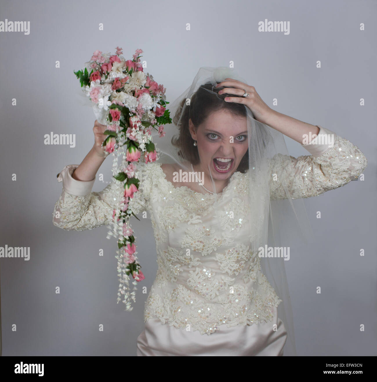 Pretty young bride holding bouquet with pink roses and screaming during ...