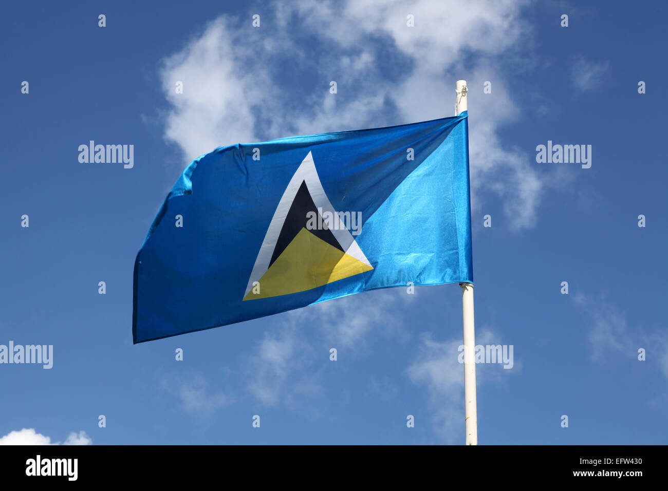 The flag of St. Lucia flying over Marigot Bay against a light blue background Stock Photo