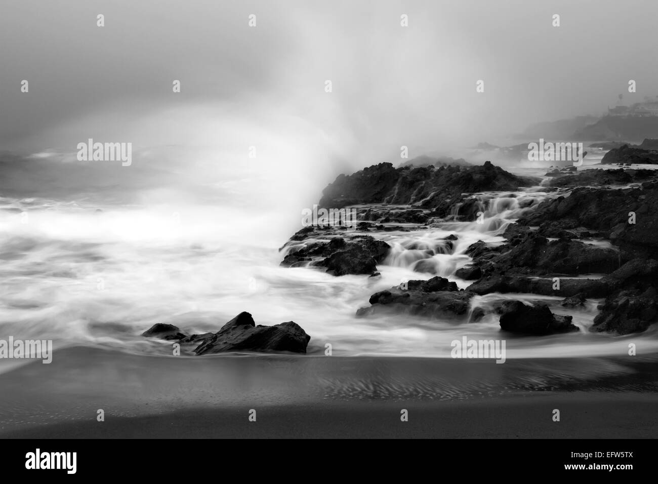 An early morning slow motion images of seawater rushing over sharp, rugged shoreline reef in Laguna Beach, California. Stock Photo