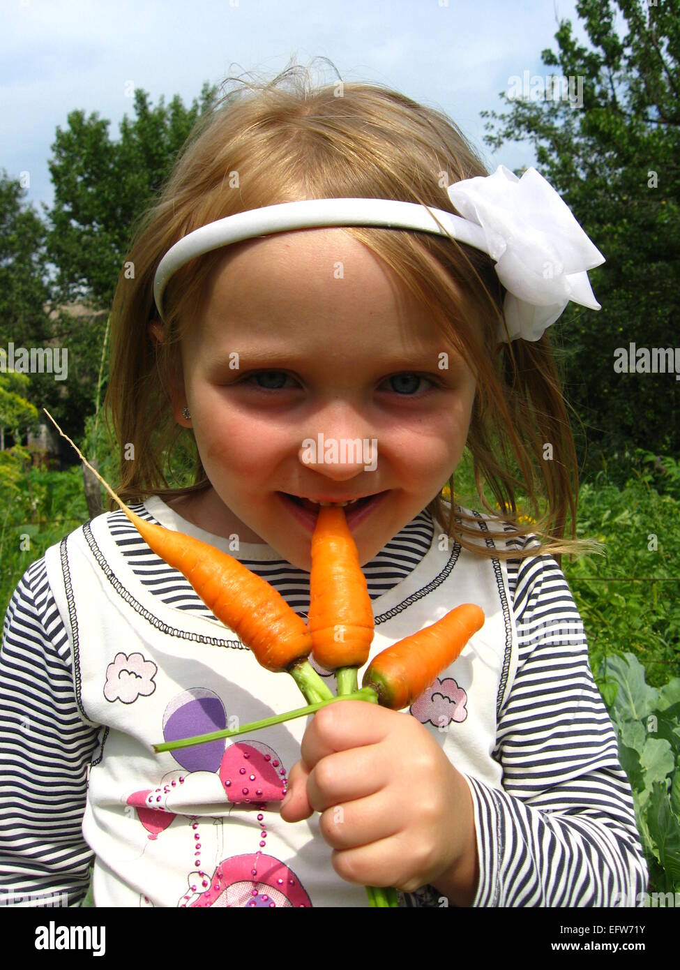 image of girl biting the ripe orange carrot Stock Photo
