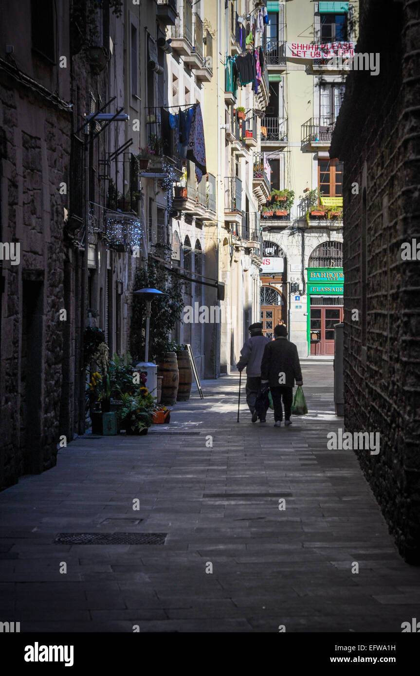 Barcelona Spain couple walking down narrow street carrying groceries Stock Photo
