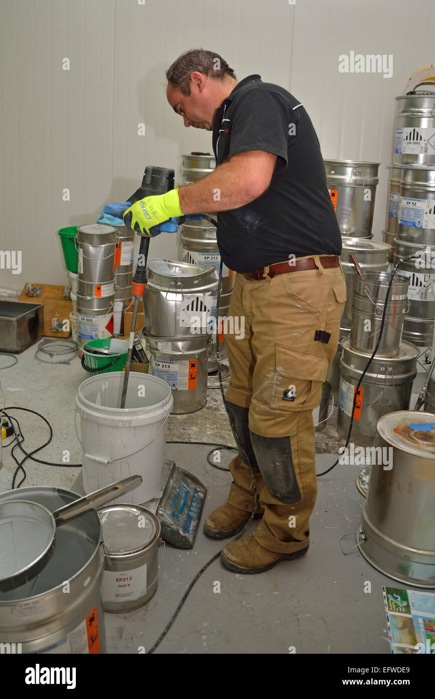 A tradesman mixes epoxy compounds for a flooring job in a commercial building Stock Photo