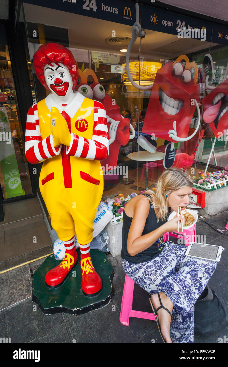 Thailand, Bangkok, Khaosan Road, Female Western Tourist Eating Pad Thai in Front of McDonalds Stock Photo