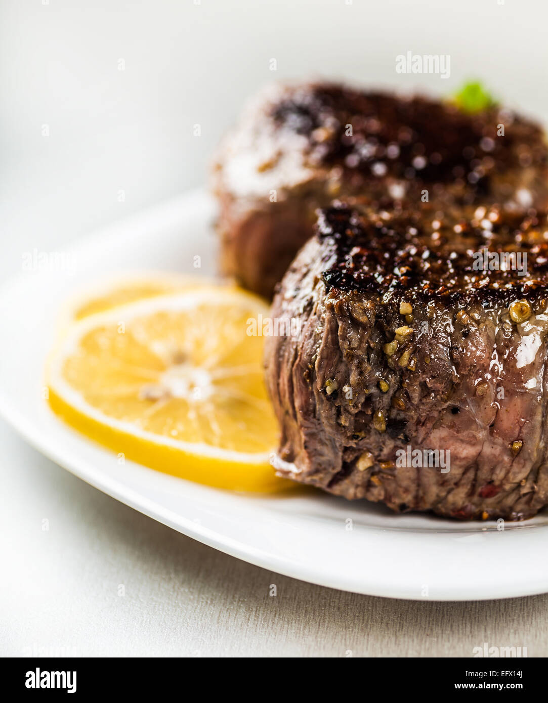 freshly prepared medallion on a plate with lemon wedges closeup Stock Photo