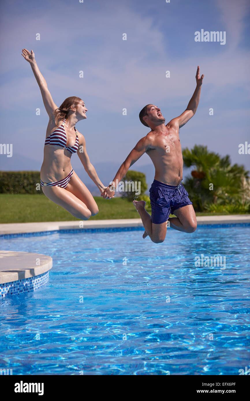 Young couple jumping in the pool on Holiday Stock Photo