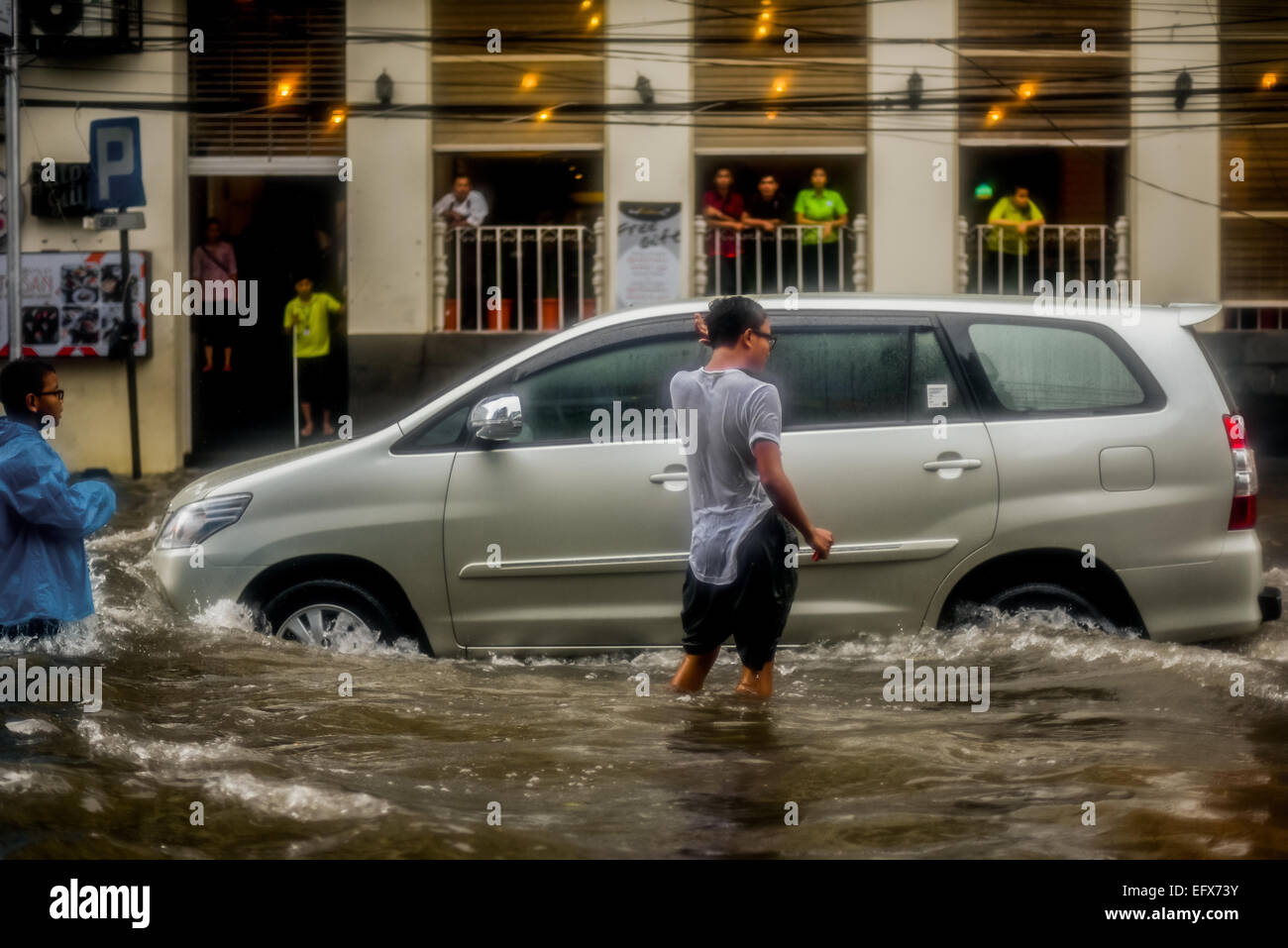 A car passing through floodwaters in Jakarta, after a continuous rain left the downtown part of the Indonesian capital city flooded. Stock Photo