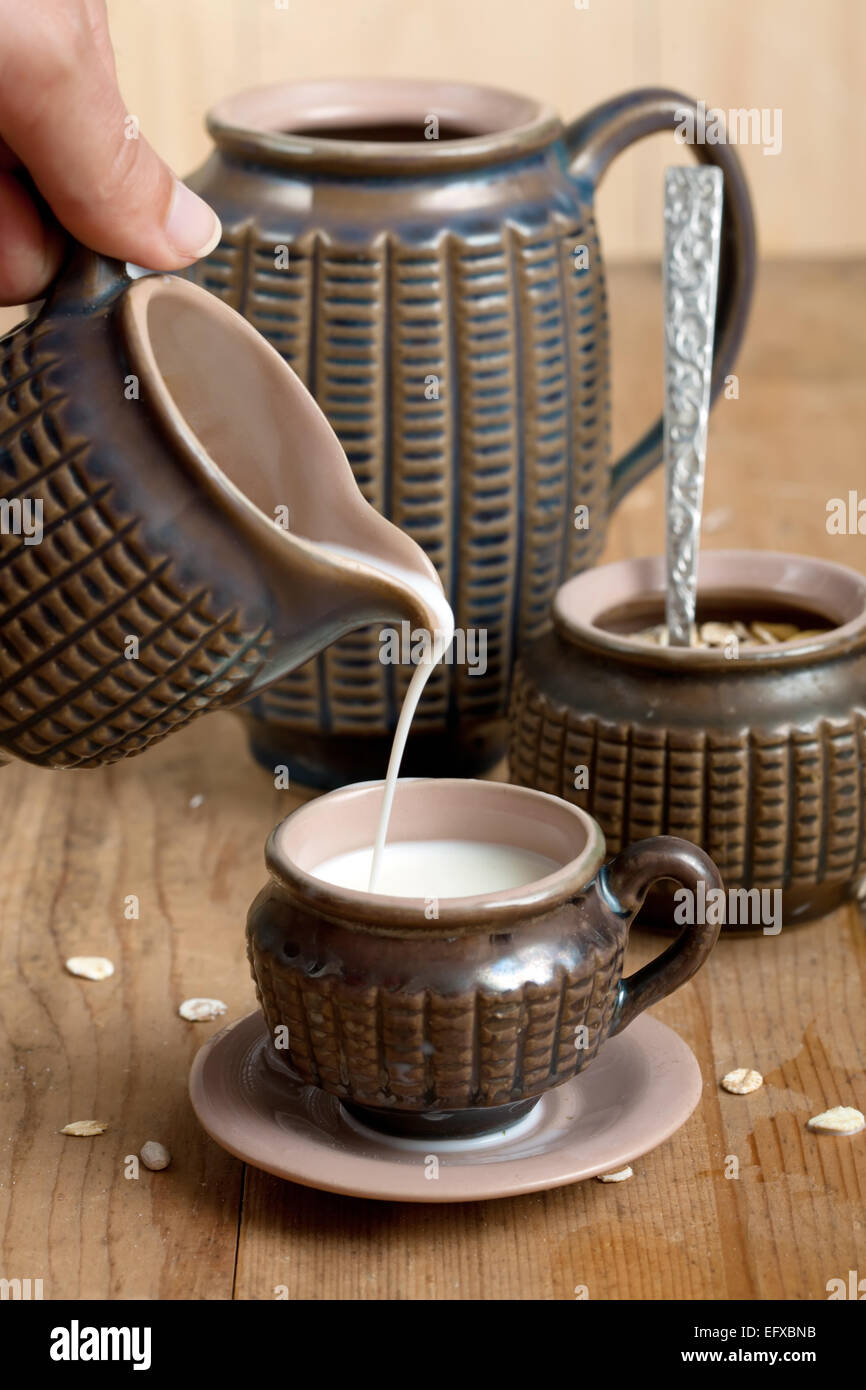 Pouring milk in vintage cup Stock Photo