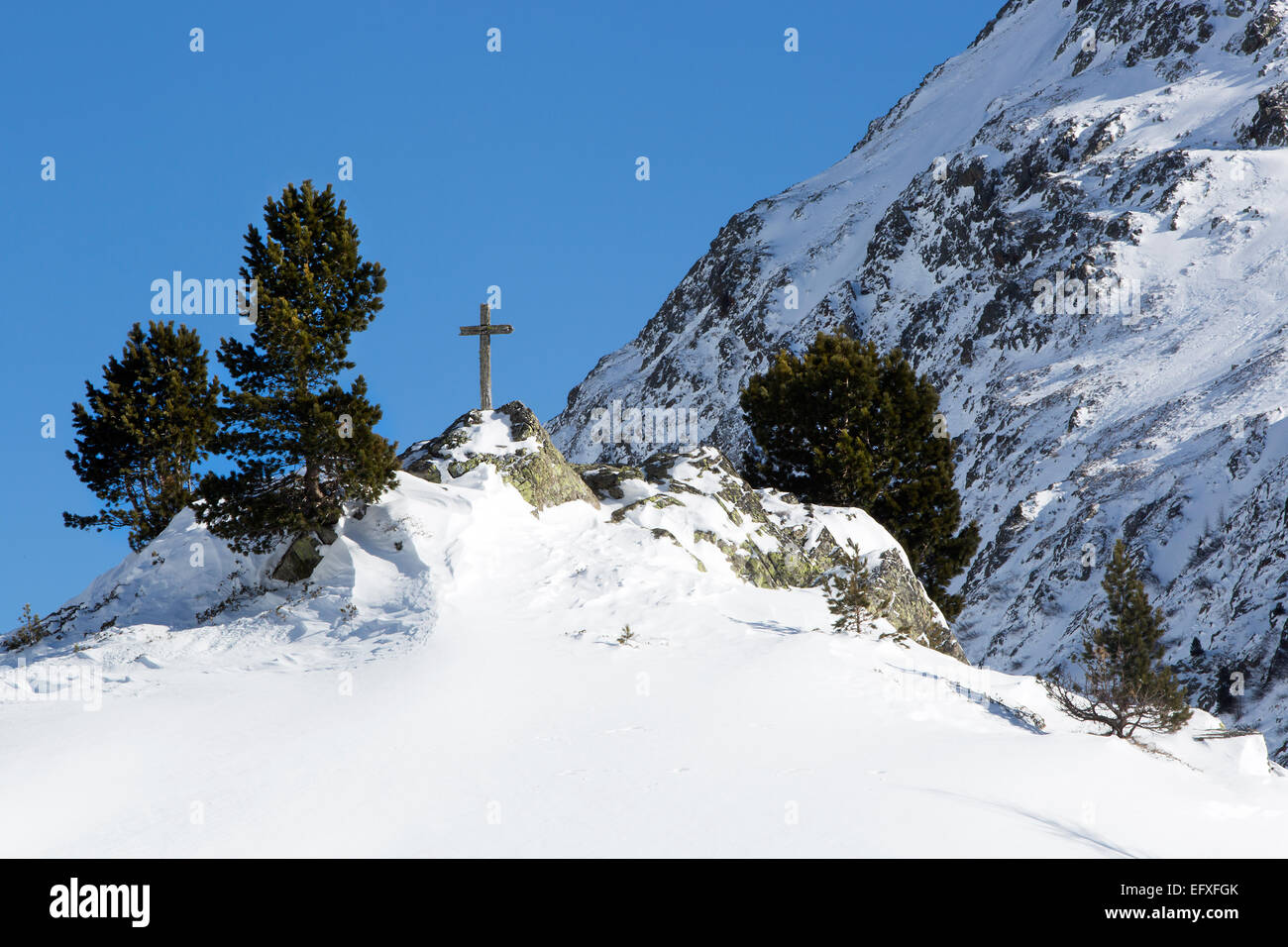 Cross in snowy mountain landscape of the Austrian Alps Stock Photo