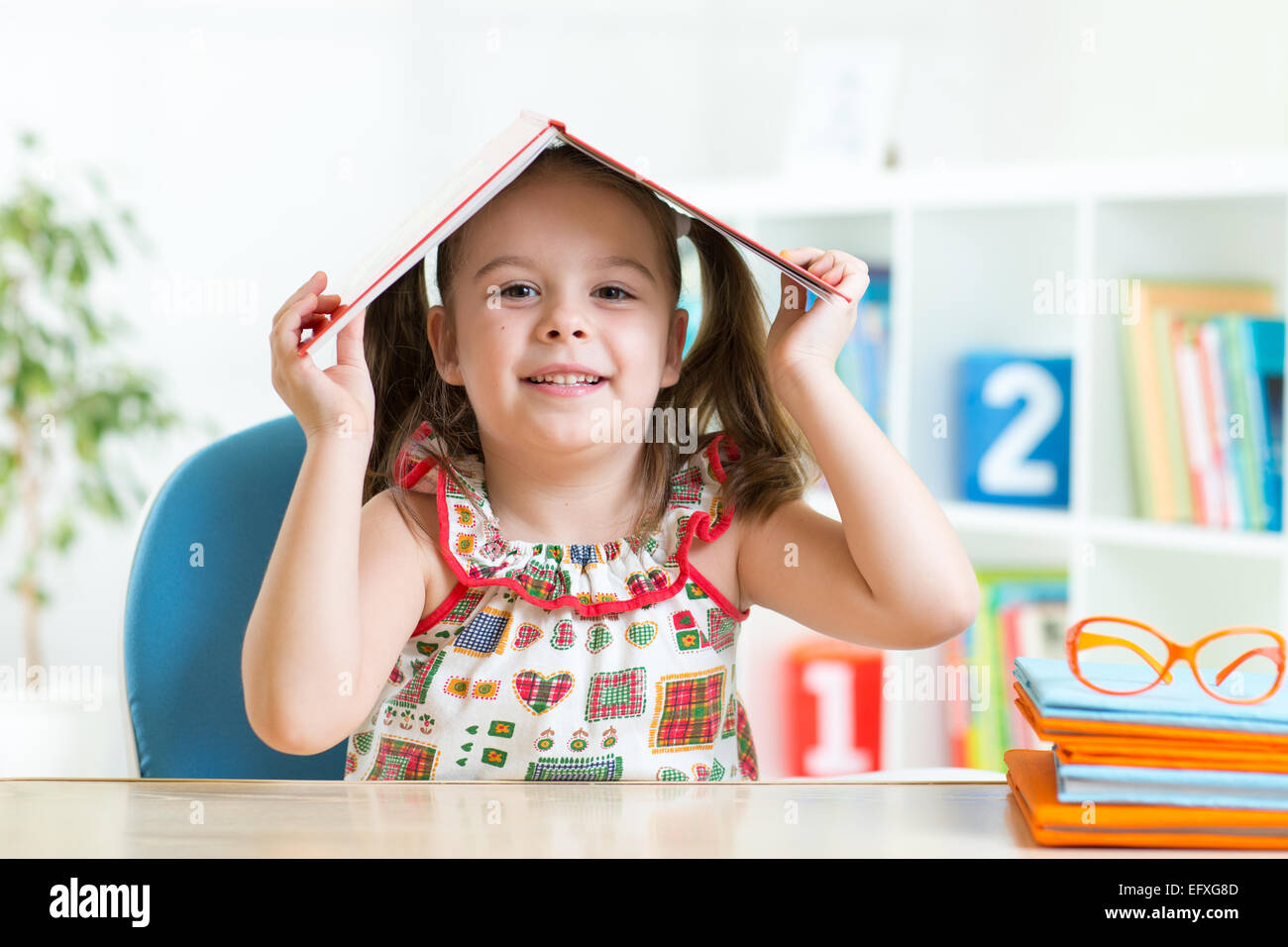 Student child with a book over her head Stock Photo - Alamy