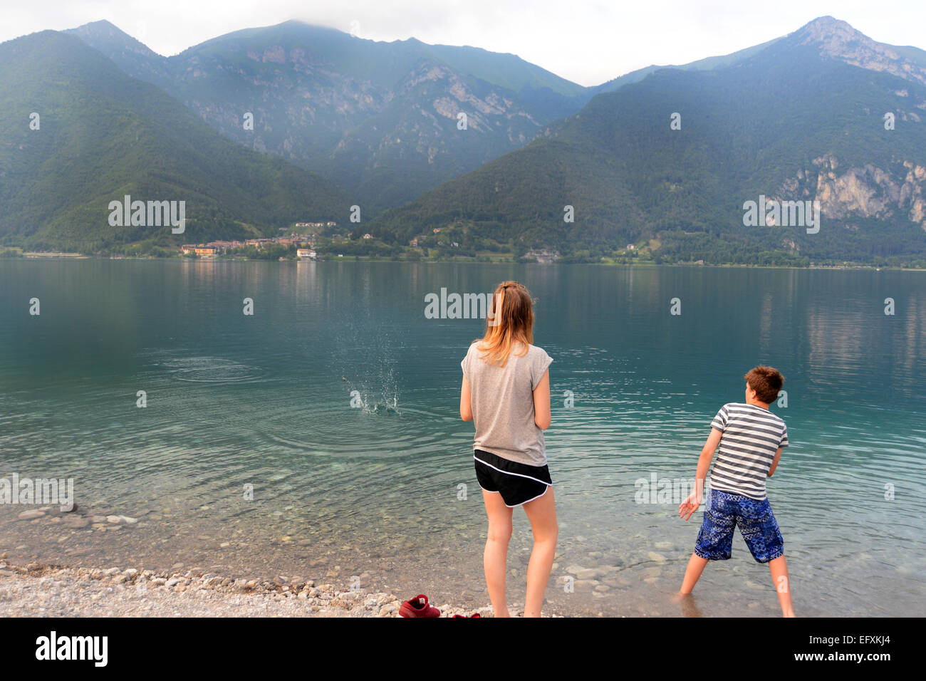 Teenagers on holiday in the Italian Lakes skimming stones. MODEL RELEASED Stock Photo