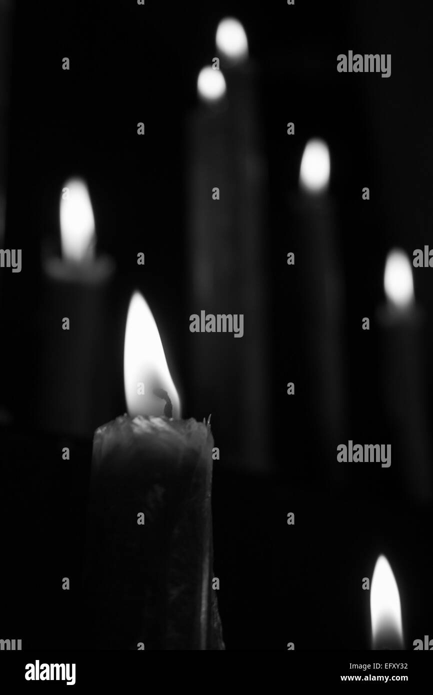 seven lit candles in a dark room at different distances Stock Photo Alamy