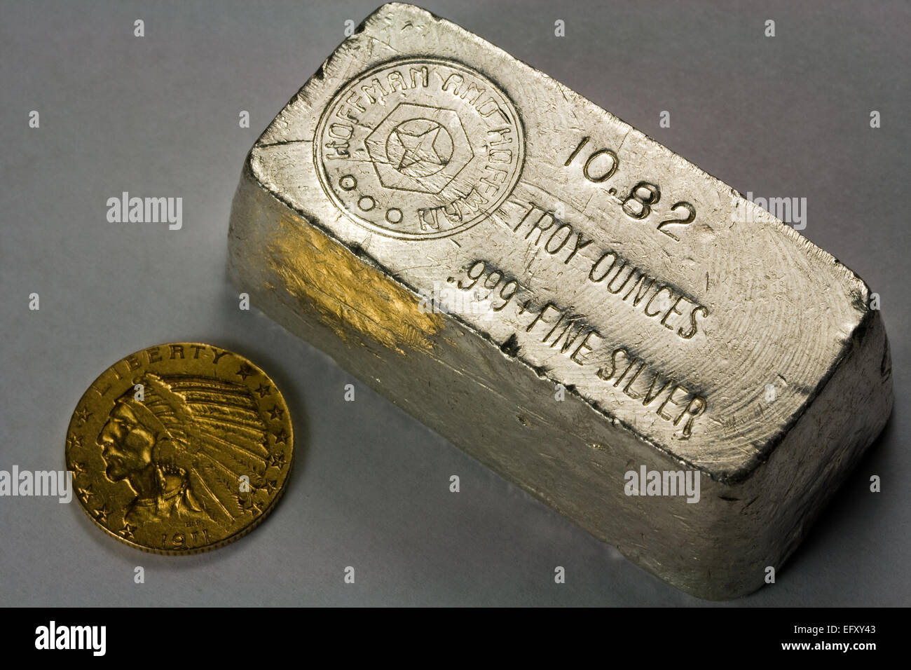 Old Poured and Stamped Silver Bullion Bar and 1911 Five Dollar United States Gold Coin Stock Photo
