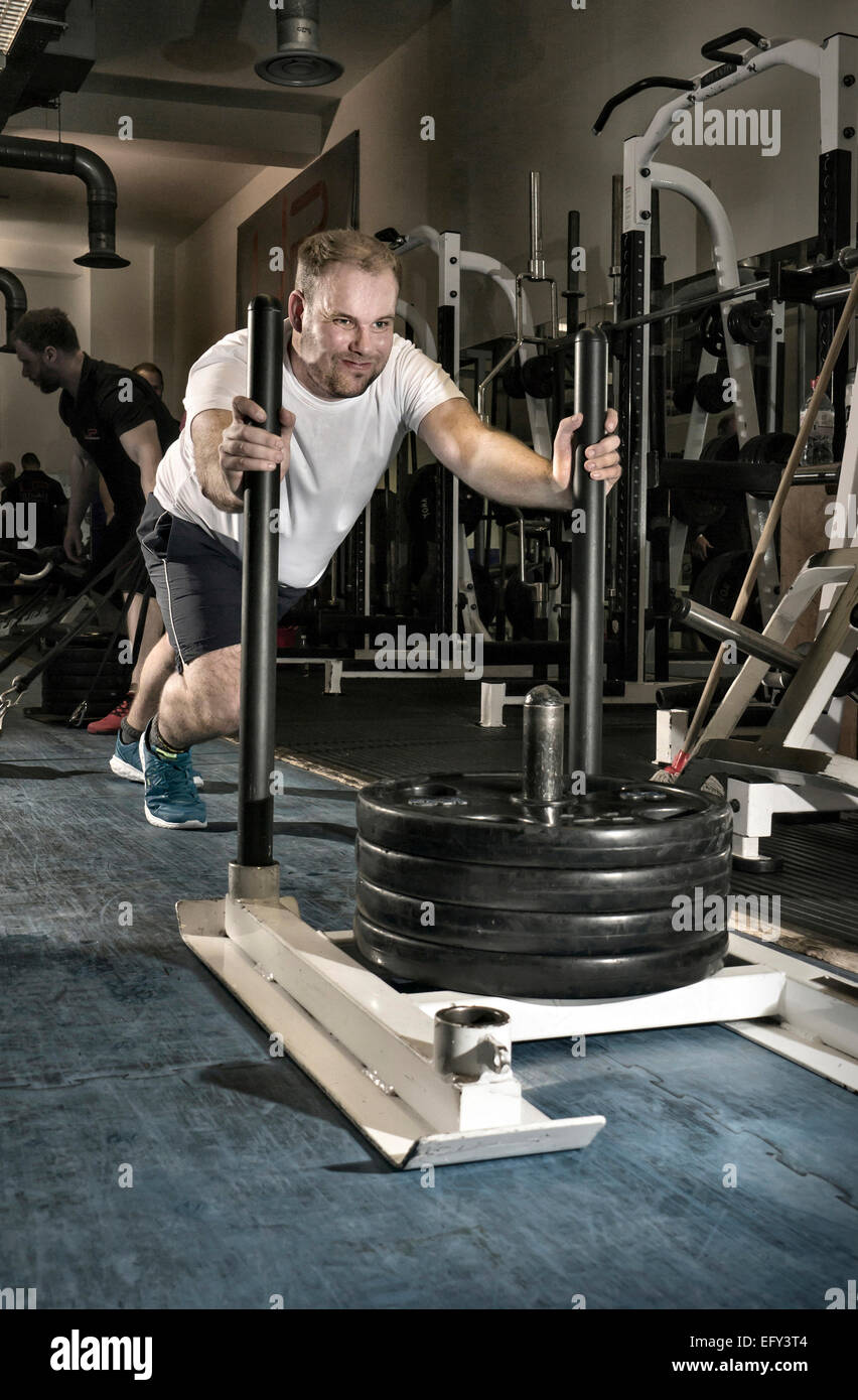 Man working out in a gym, pushing a sledge of weights Stock Photo Alamy
