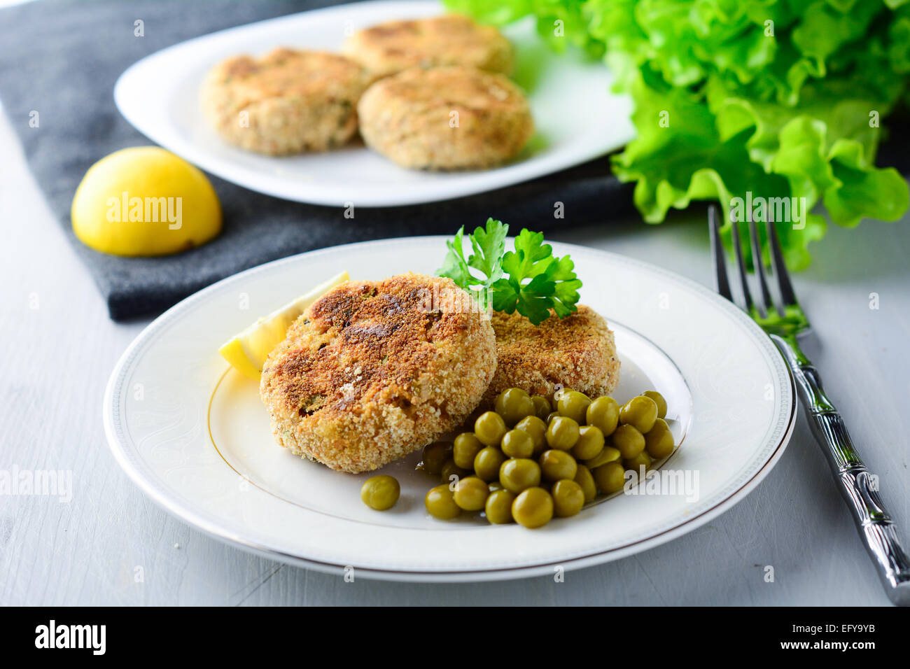 Patties with canned peas and fresh green salad on white plate Stock Photo