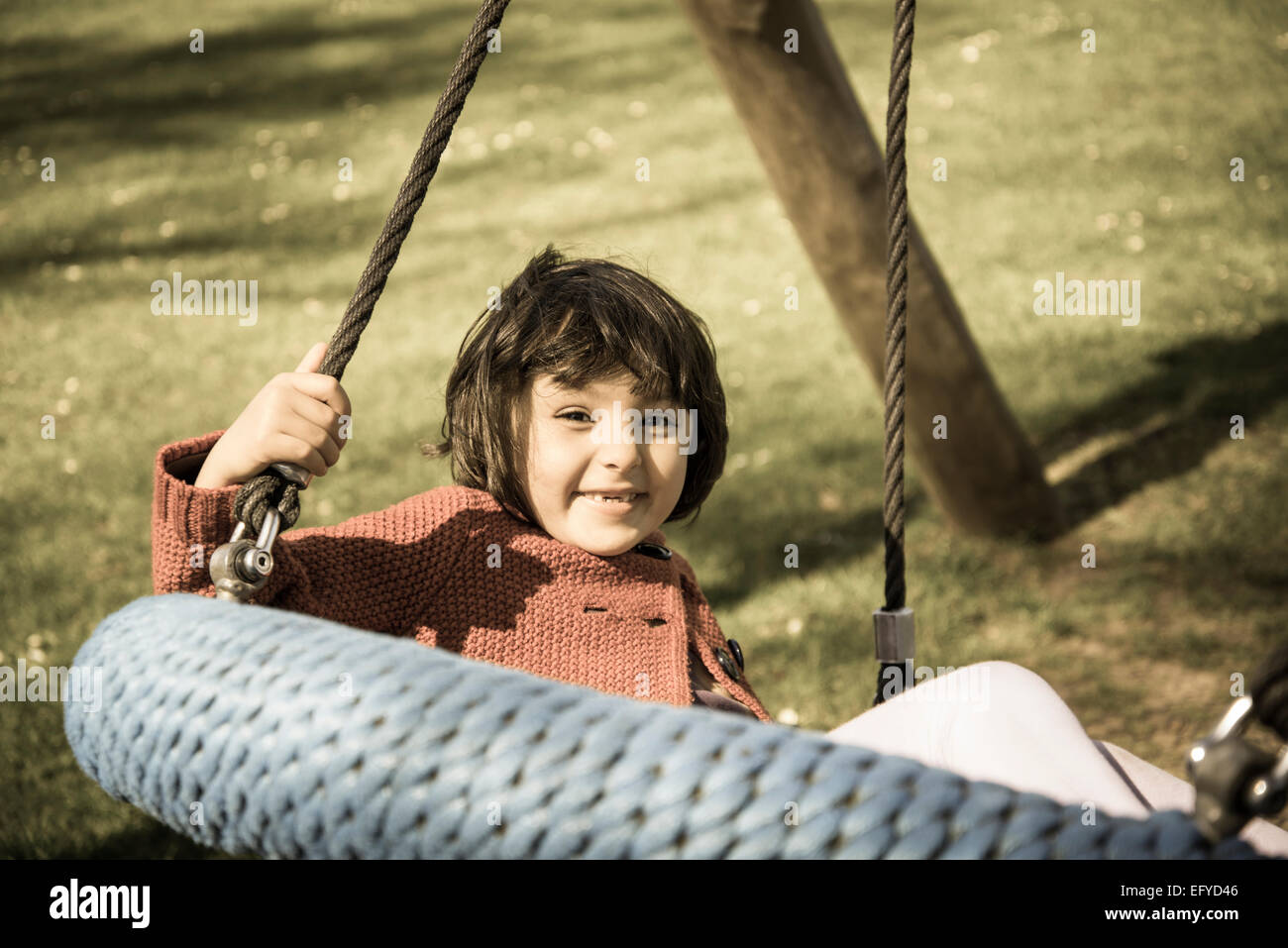 Little girl in a swing in playground Stock Photo
