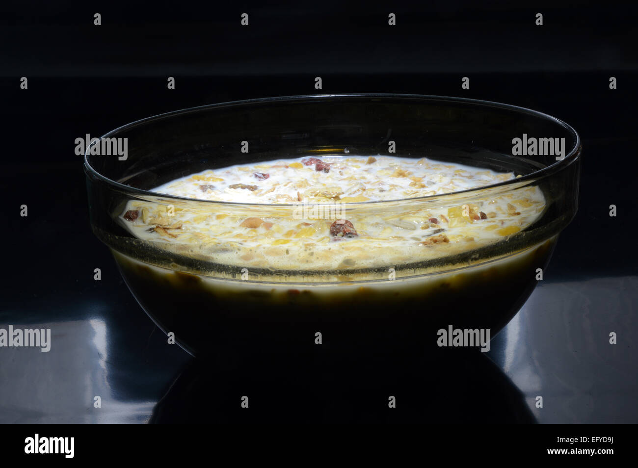 Black Transparent cup with muesli, milk tucked on a black background Stock Photo