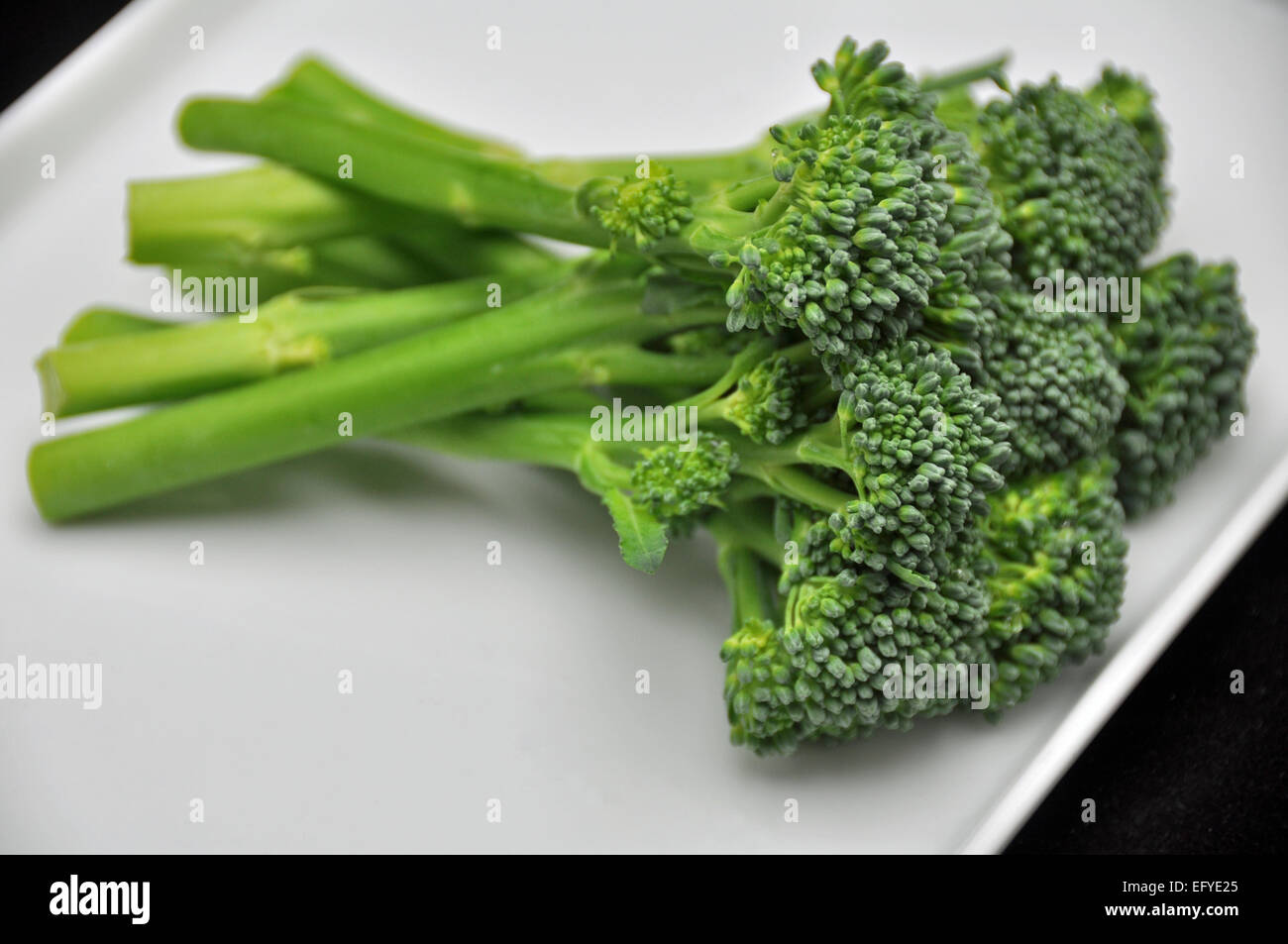 Tenderstem broccoli spears on a white rectangular plate, black
