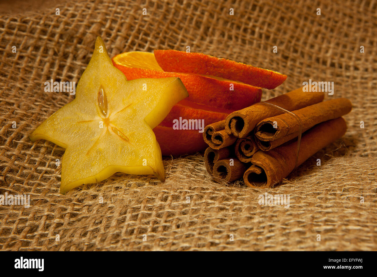 Cinnamon sticks, orange slices and star fruit slices on jute Stock Photo