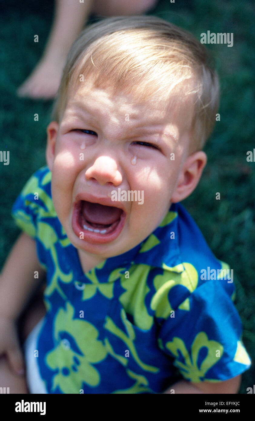 Two big tears drip from eyes of a crying young American baby boy whose