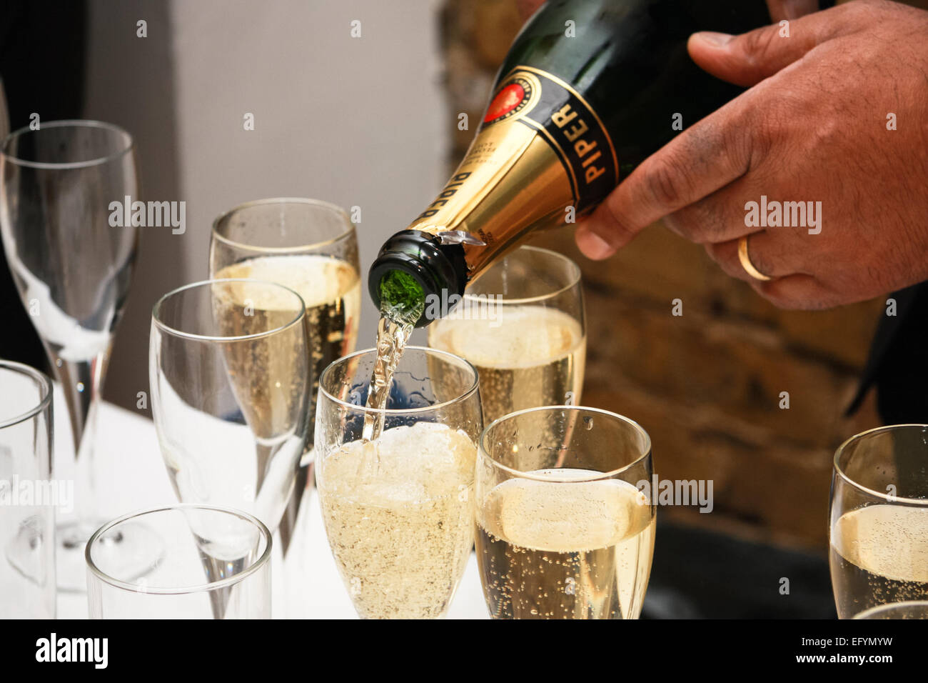 Man with ring on finger pouring champagne into glass Stock Photo - Alamy