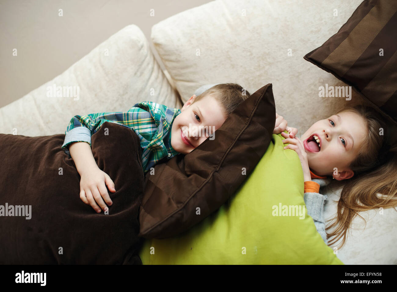 boy fights with girl pillow at home Stock Photo