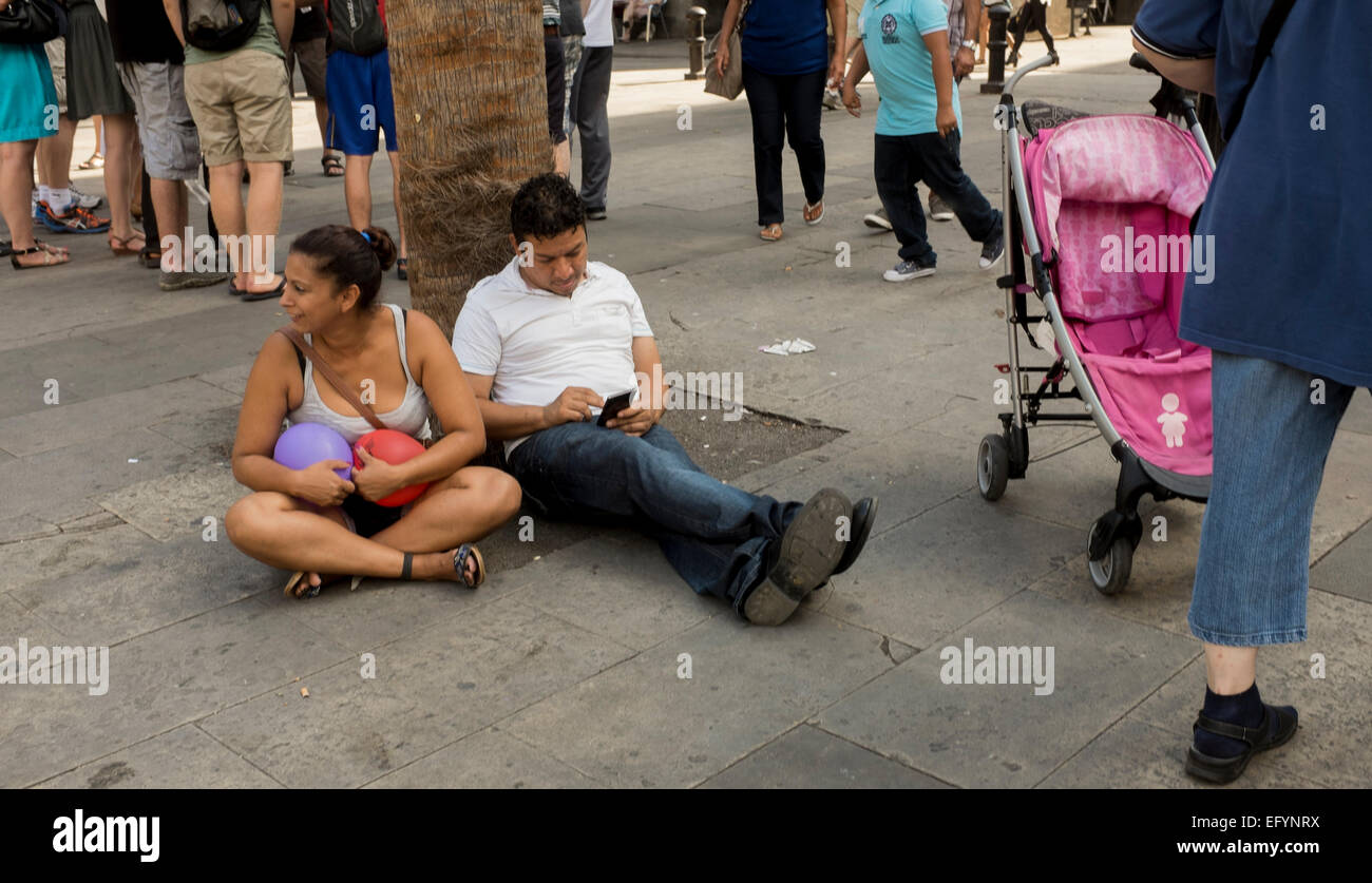 A couple relaxing against a palm-tree on the Rambla street in Barcelona Stock Photo