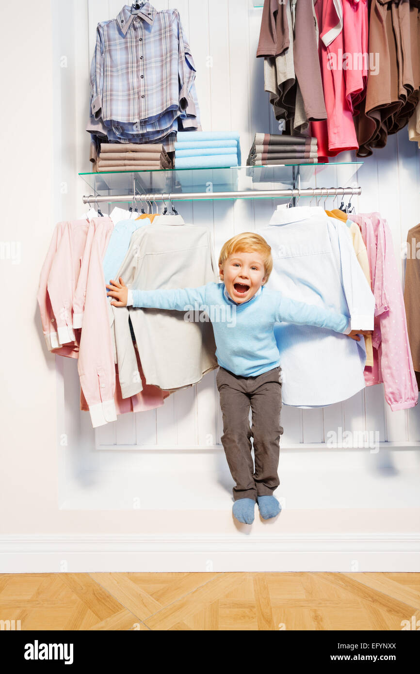 Laughing boy standing among clothes in the shop Stock Photo - Alamy