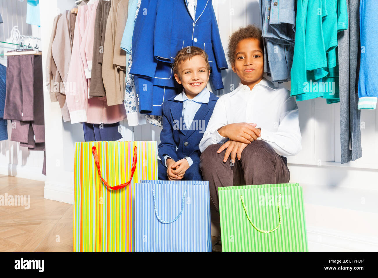 https://c8.alamy.com/comp/EFYPDP/two-boys-sitting-under-hangers-with-clothes-EFYPDP.jpg