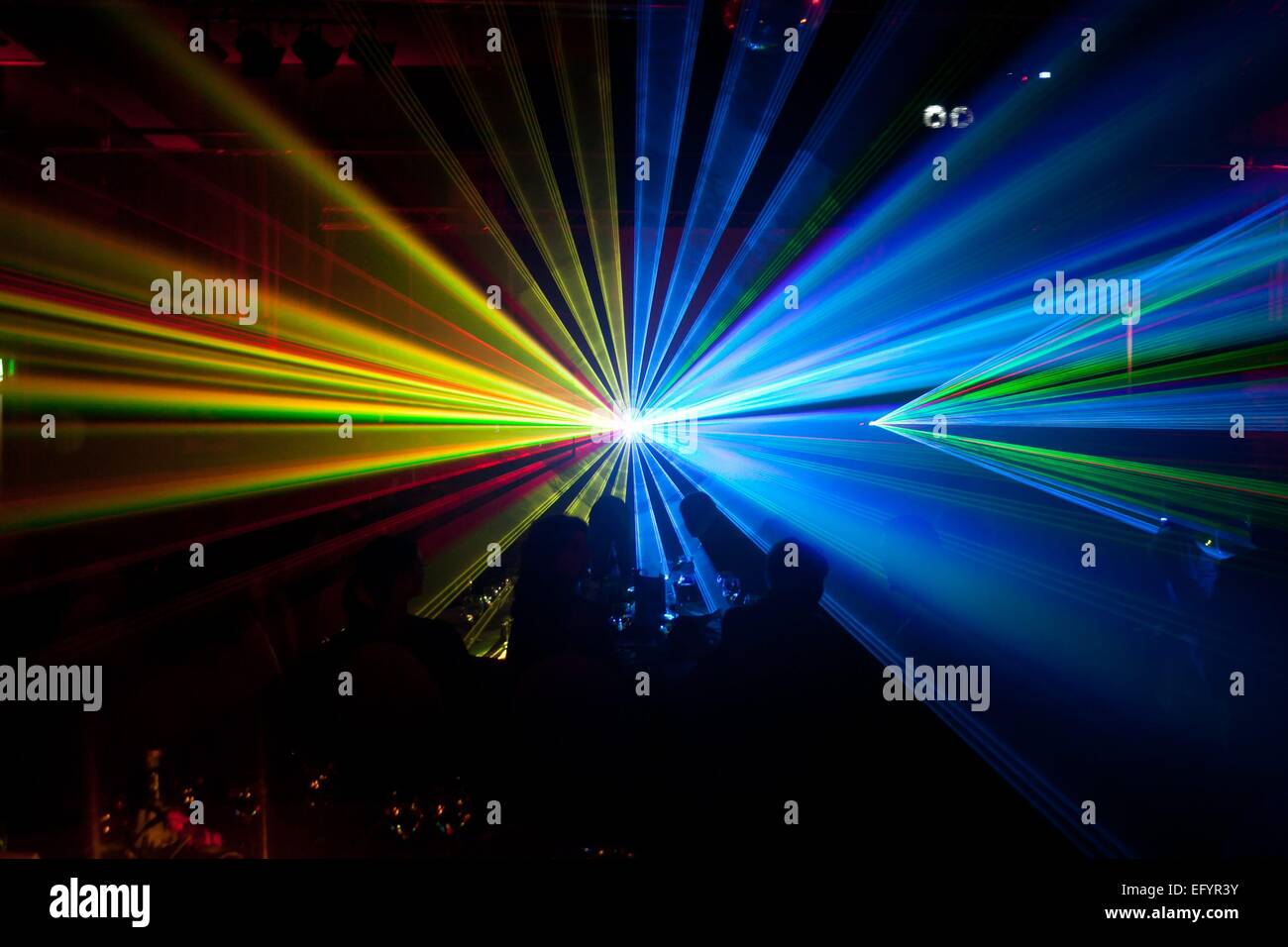 an audience enjoys a great lightshow, lasershow in yellow and blue colours  (captured in between the laser rays Stock Photo - Alamy