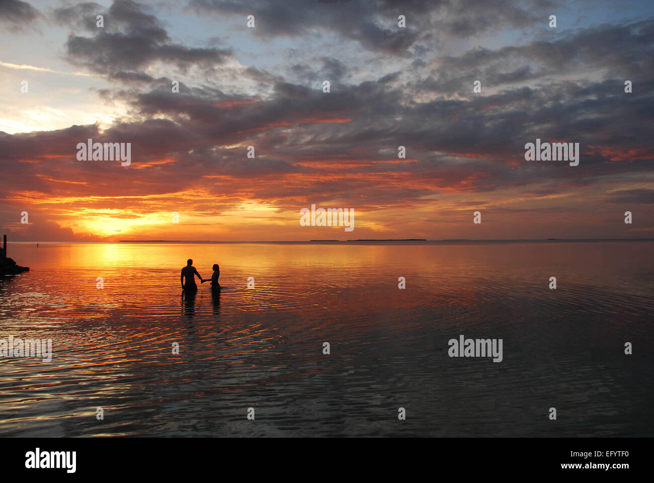 A couple stands in the sunset; Florida Keys, MM88. Stock Photo