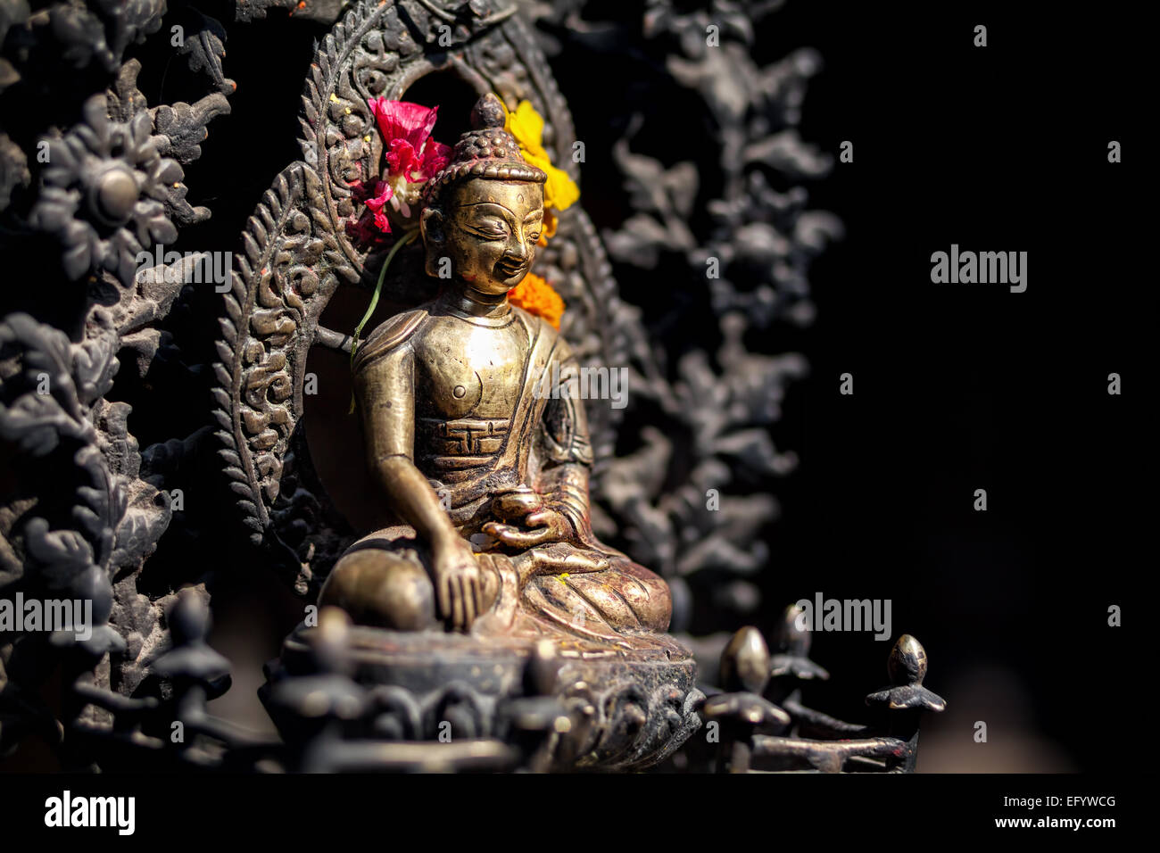 Buddha statue with yellow and red flowers in Patan, Nepal Stock Photo