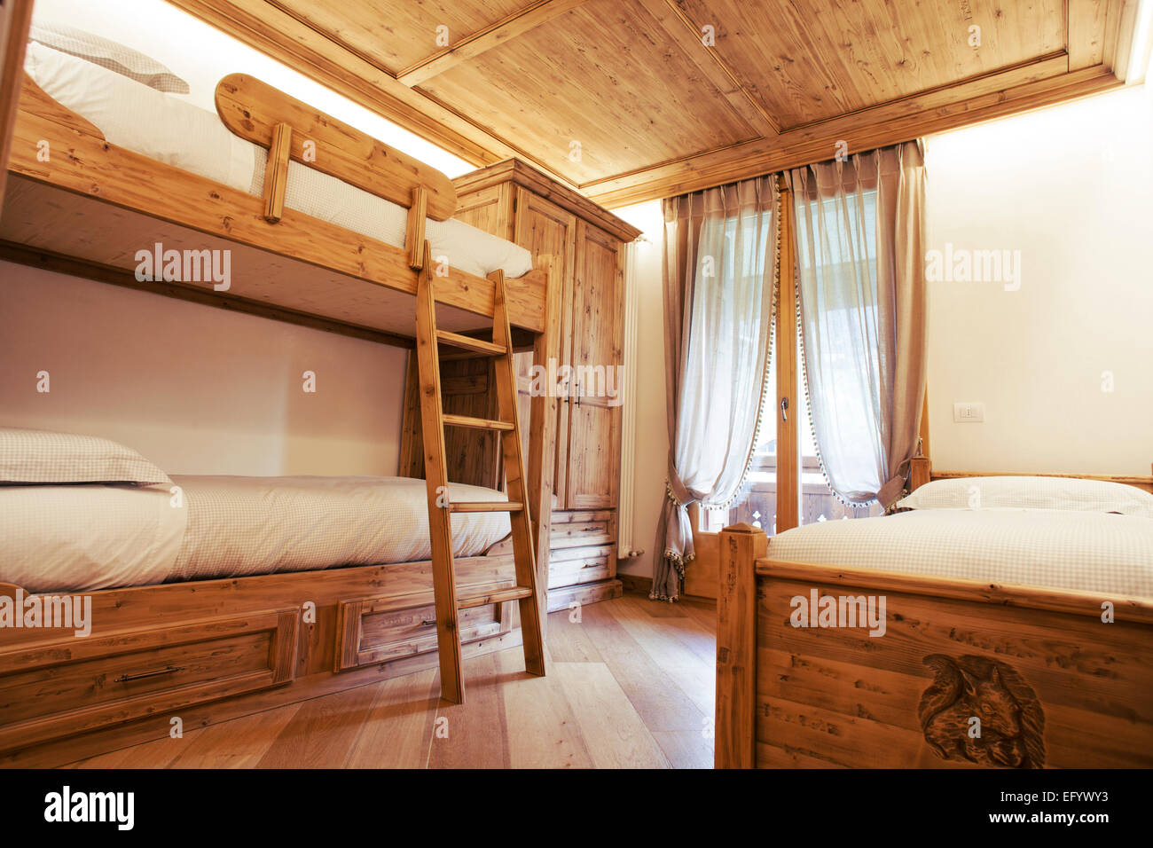 Triple room with single and bunk beds in a children's bedroom. Alpine style Stock Photo