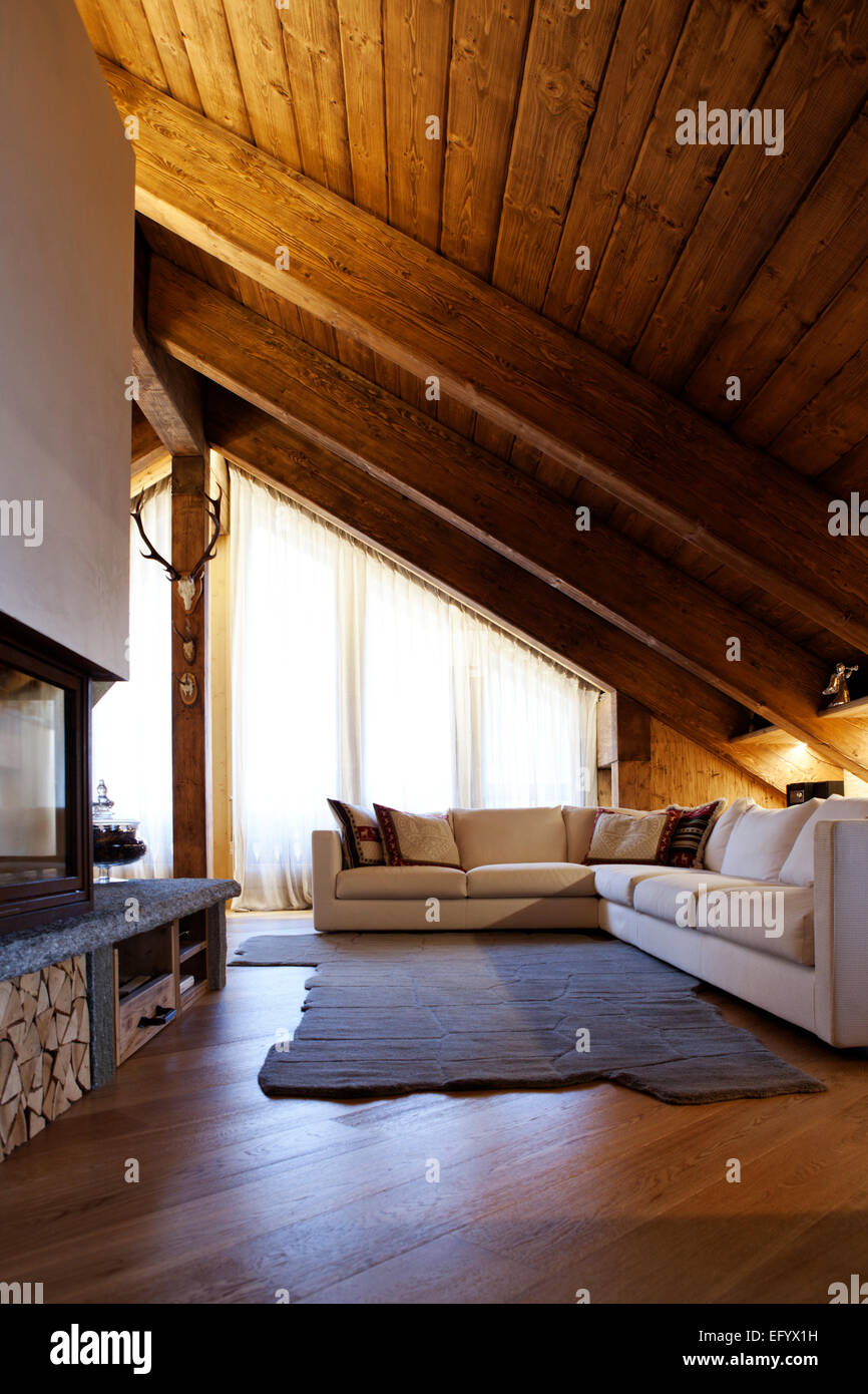 Prestigious luxury Alpine living room with modern corner white sofa and fireplace Stock Photo