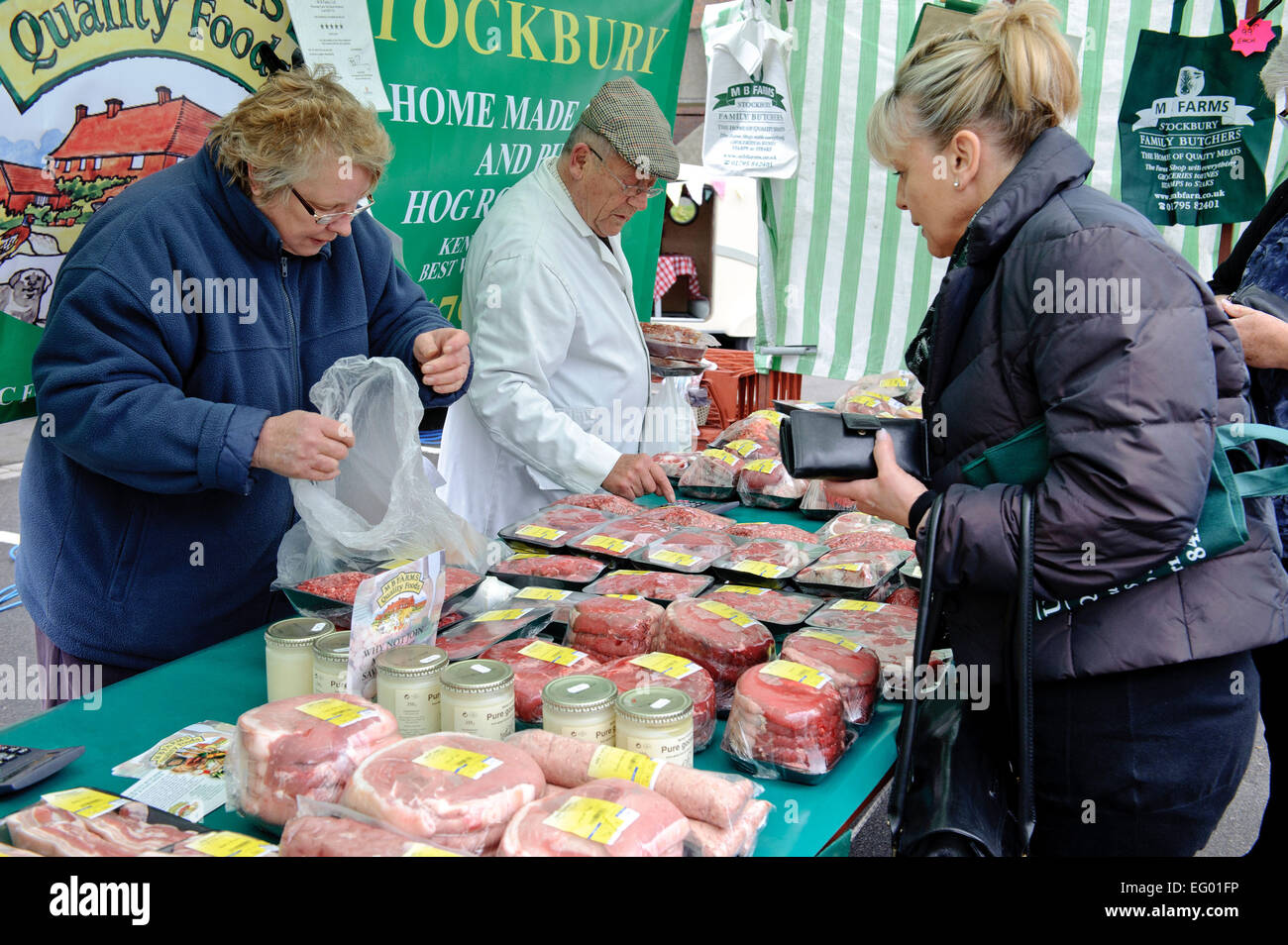 Middle aged woman buying meat product from stall at farmers market Kent UK Stock Photo