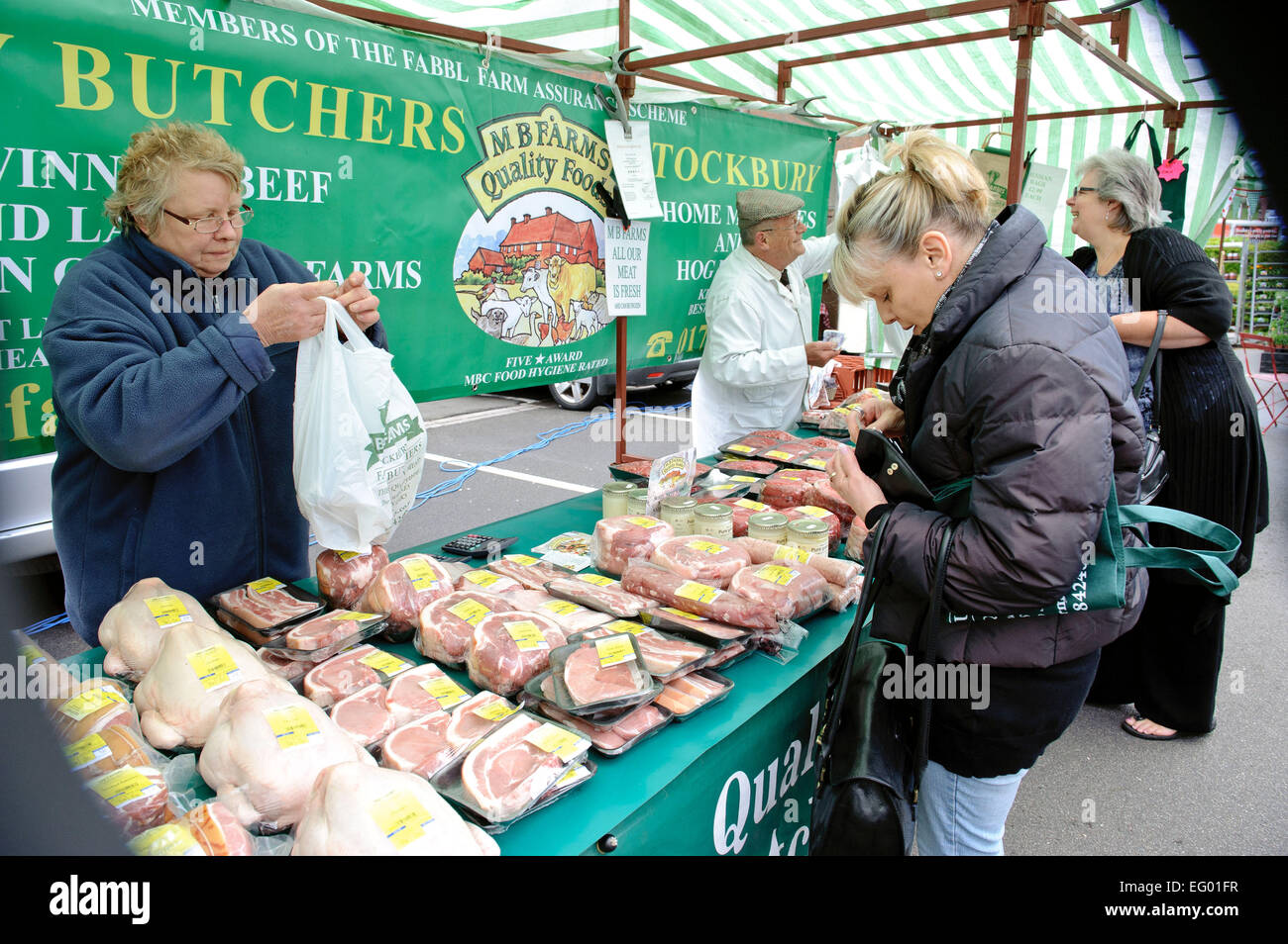 Middle aged woman buying meat product from stall at farmers market Kent UK Stock Photo