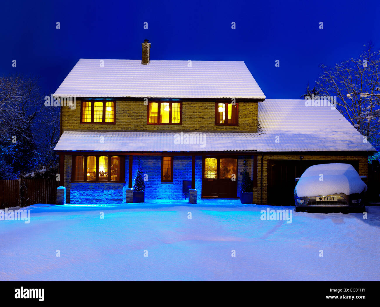 Night time image of large 4 5 bedroom executive style detached house winter exterior covered in snow Kent UK Stock Photo