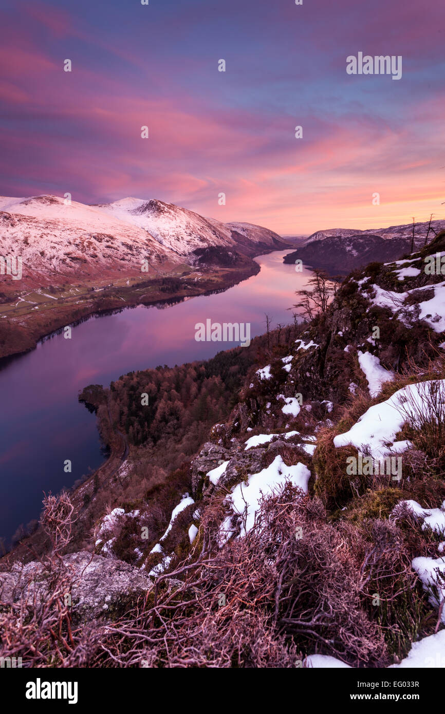 A view along Lake Thirlmere in the English Lake District after sunset, with snow on the mountains and pink in the sky. Stock Photo