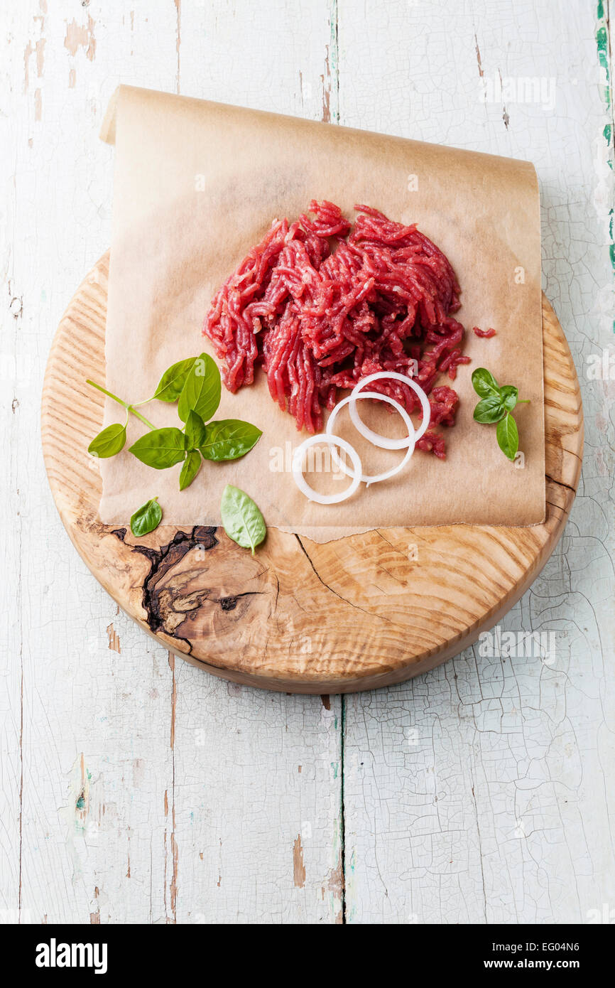 Fresh minced meat with onion on wooden cutting board on blue background Stock Photo