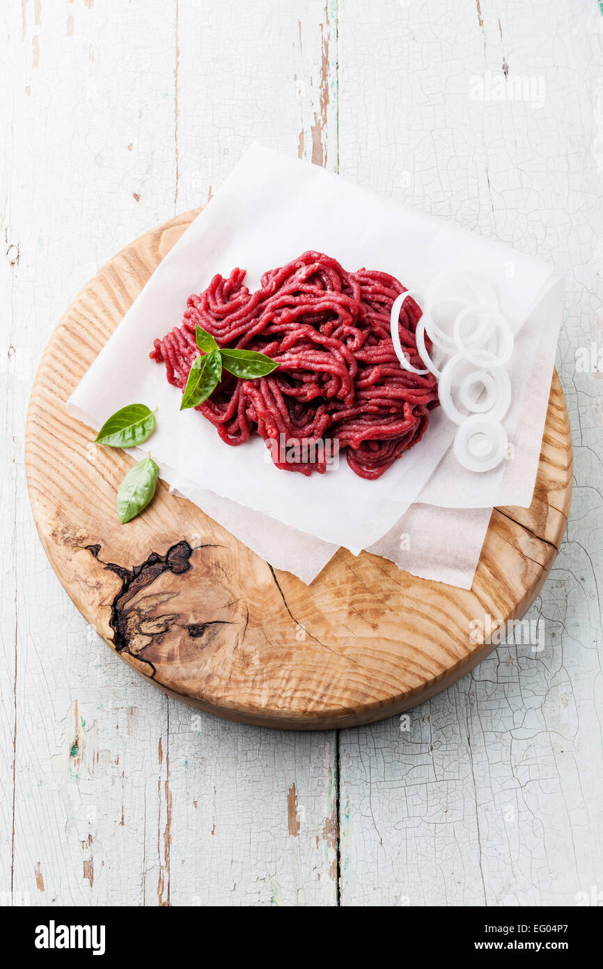 Fresh minced meat with onion on wooden cutting board on blue background Stock Photo