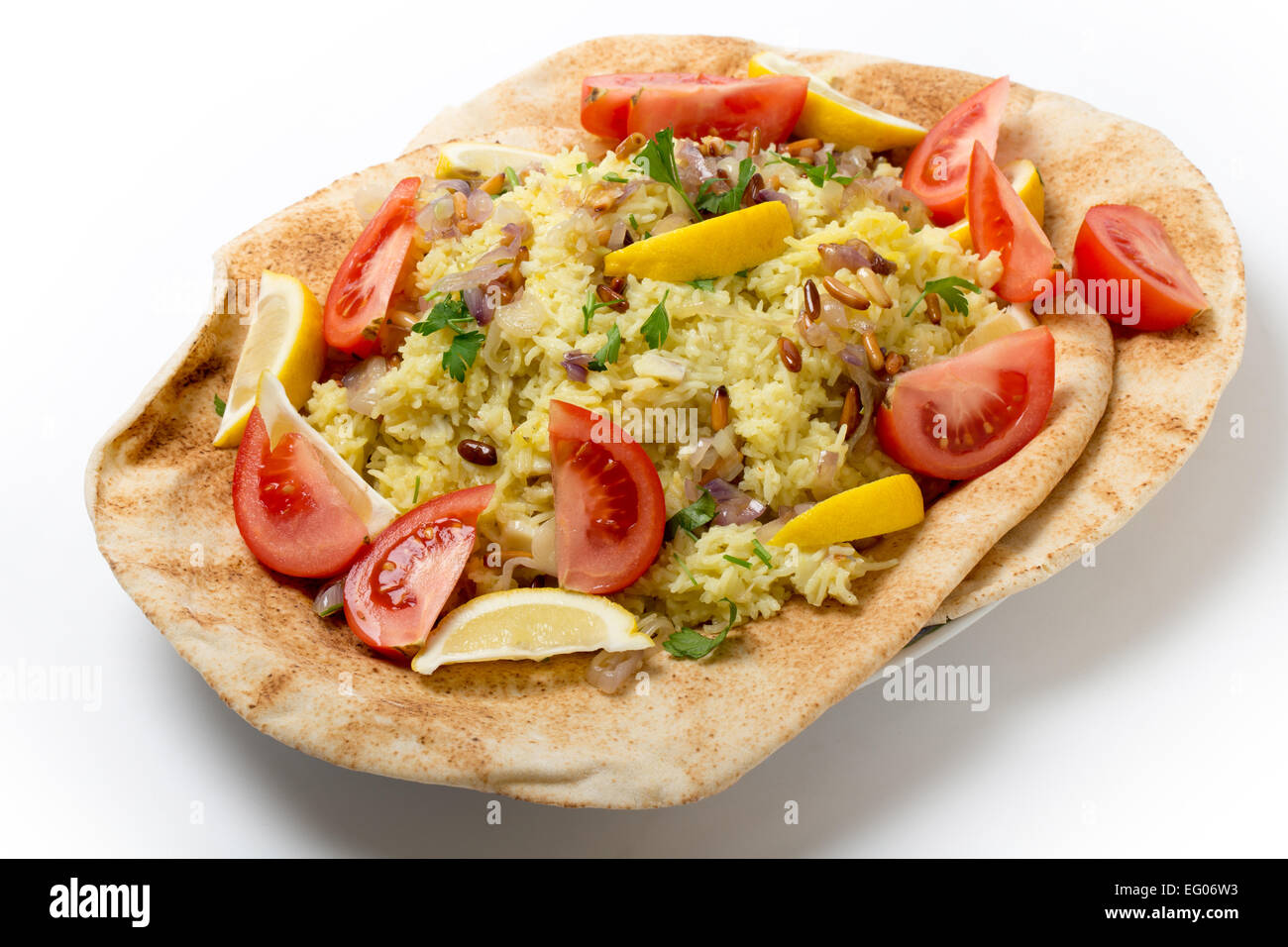 Levantine sayyadiyya, fish pilaf in saffron rice, garnished with lemon, tomato, pine-nuts and fried onion, on a bed of bread. Stock Photo