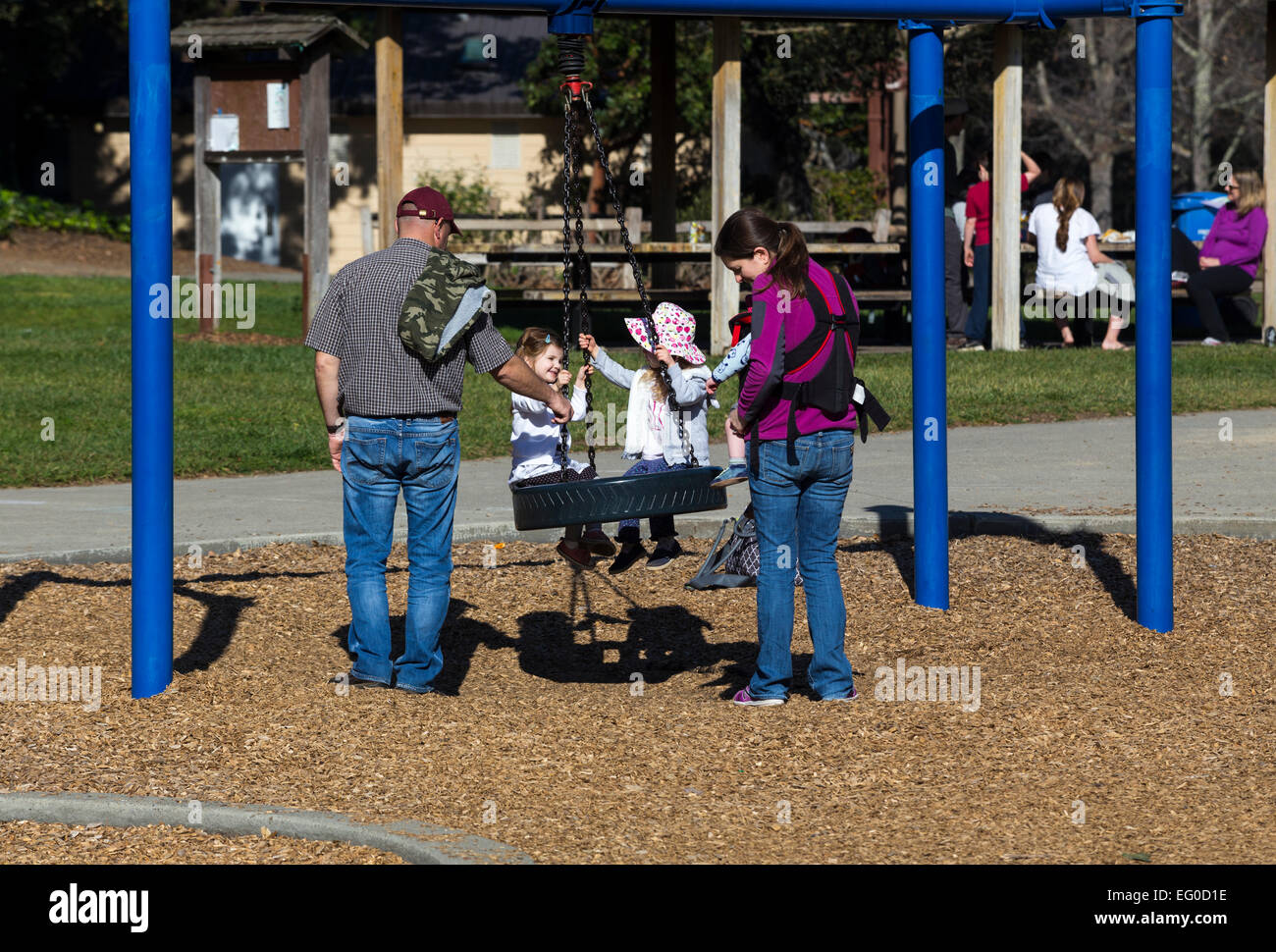 Parents, young girls, children, on swing, playground, Pioneer Park, city, Novato, California, United States Stock Photo
