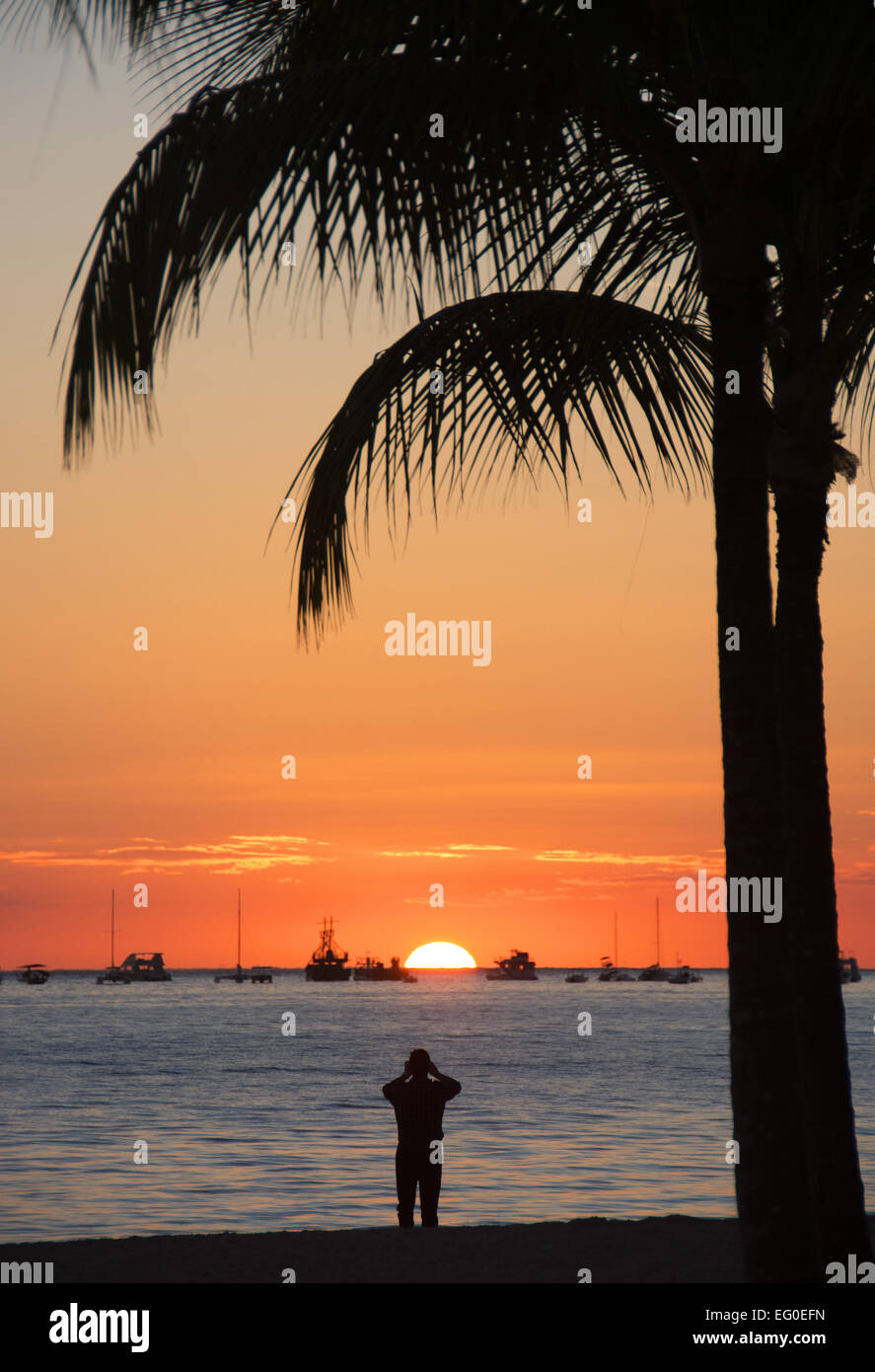 DOMINICAN REPUBLIC. A holidaymaker photographing the sunrise at Punta Cana beach on the Atlantic coast. 2015. Stock Photo