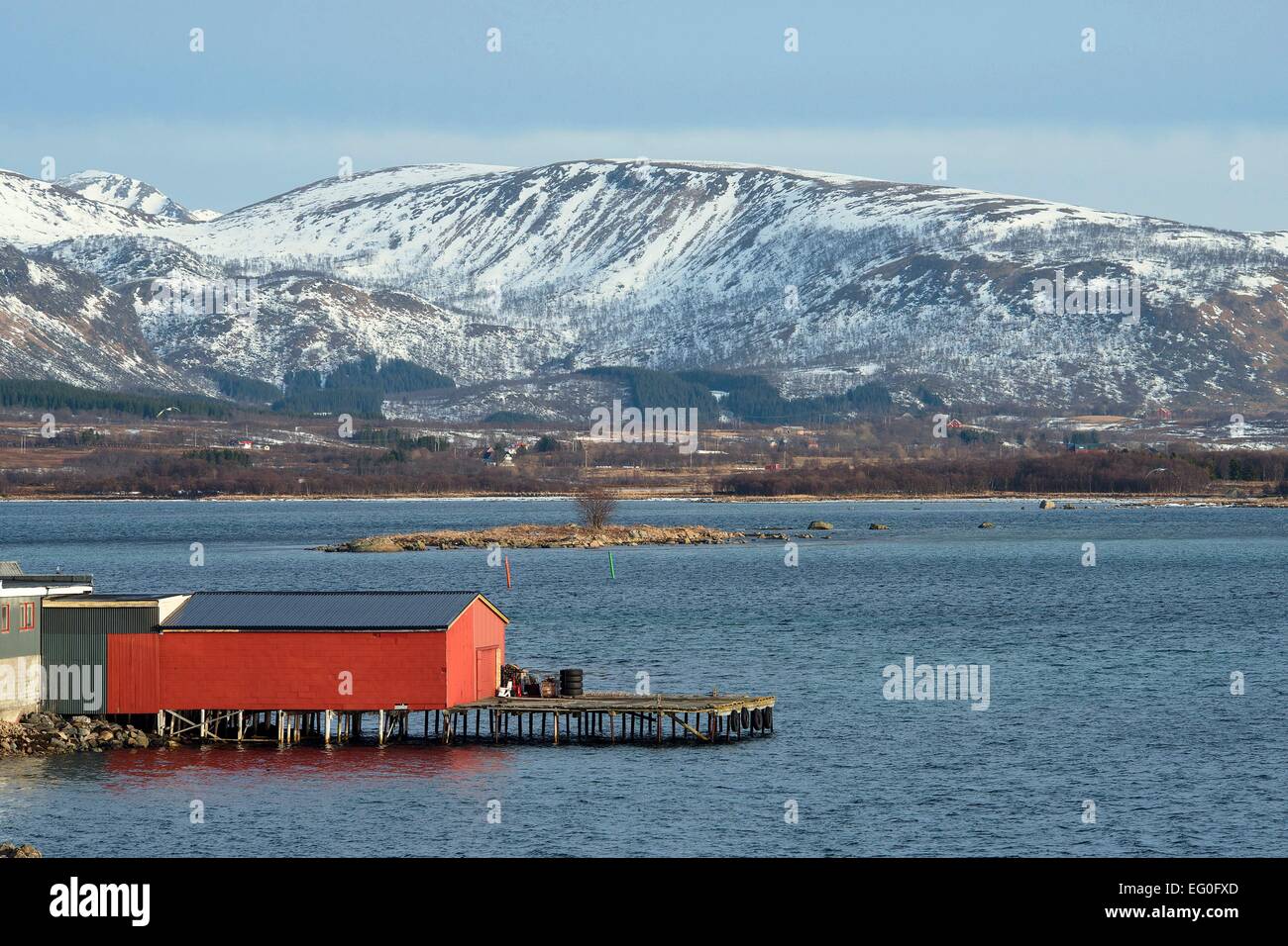 Mountainous snow covered island landscape with big red fisherman's cottage on the water, 26 February 2014 Stock Photo