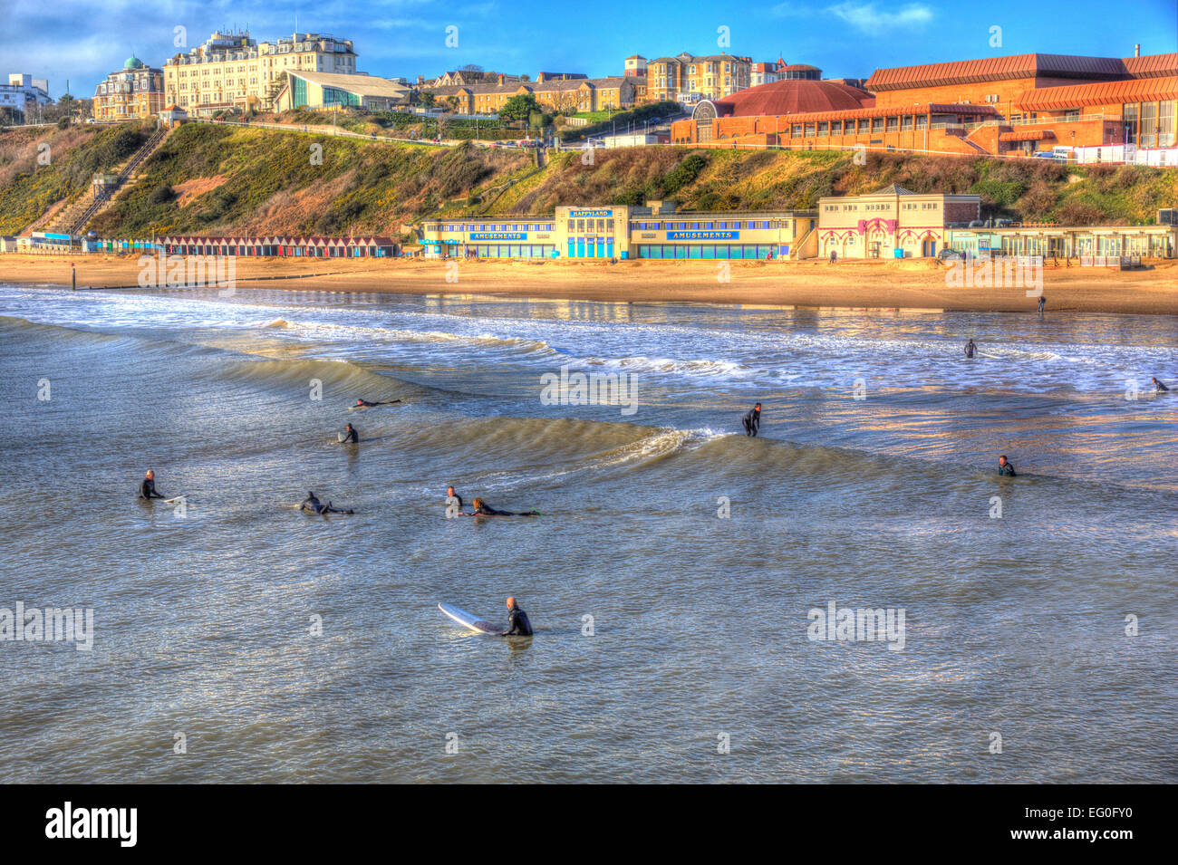 Surfers surfing Bournemouth beach Dorset England UK like a painting in vivid bright colour HDR